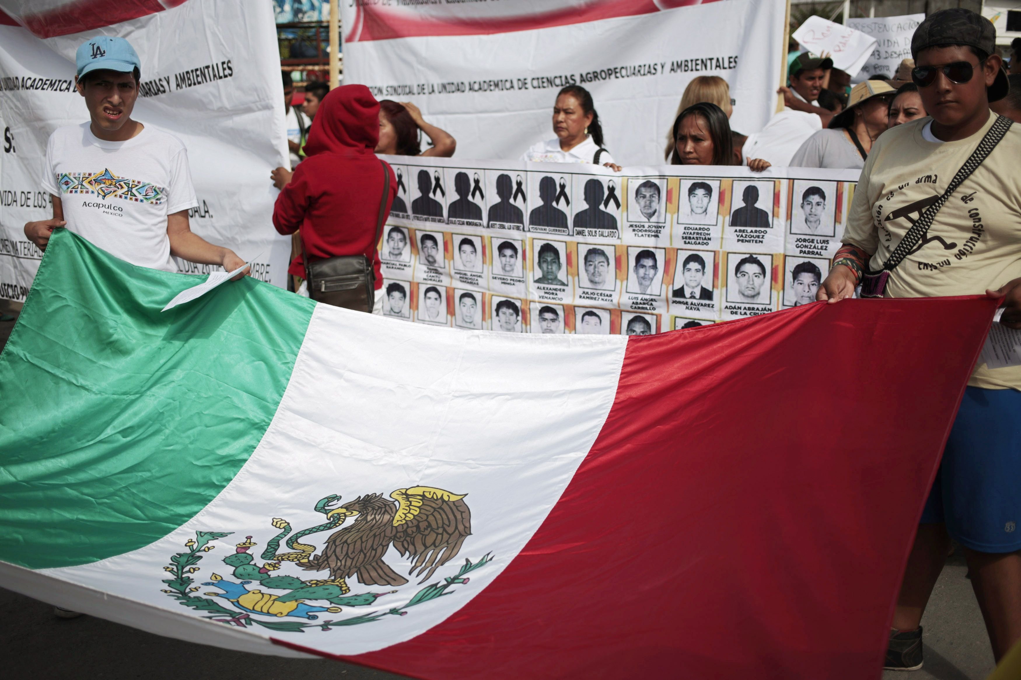 People hold a Mexican flag during a demonstration to demand information for the 43 missing students of the Ayotzinapa teachers' training college, in Iguala, the southern Mexican state of Guerrero on Oct. 22, 2014.