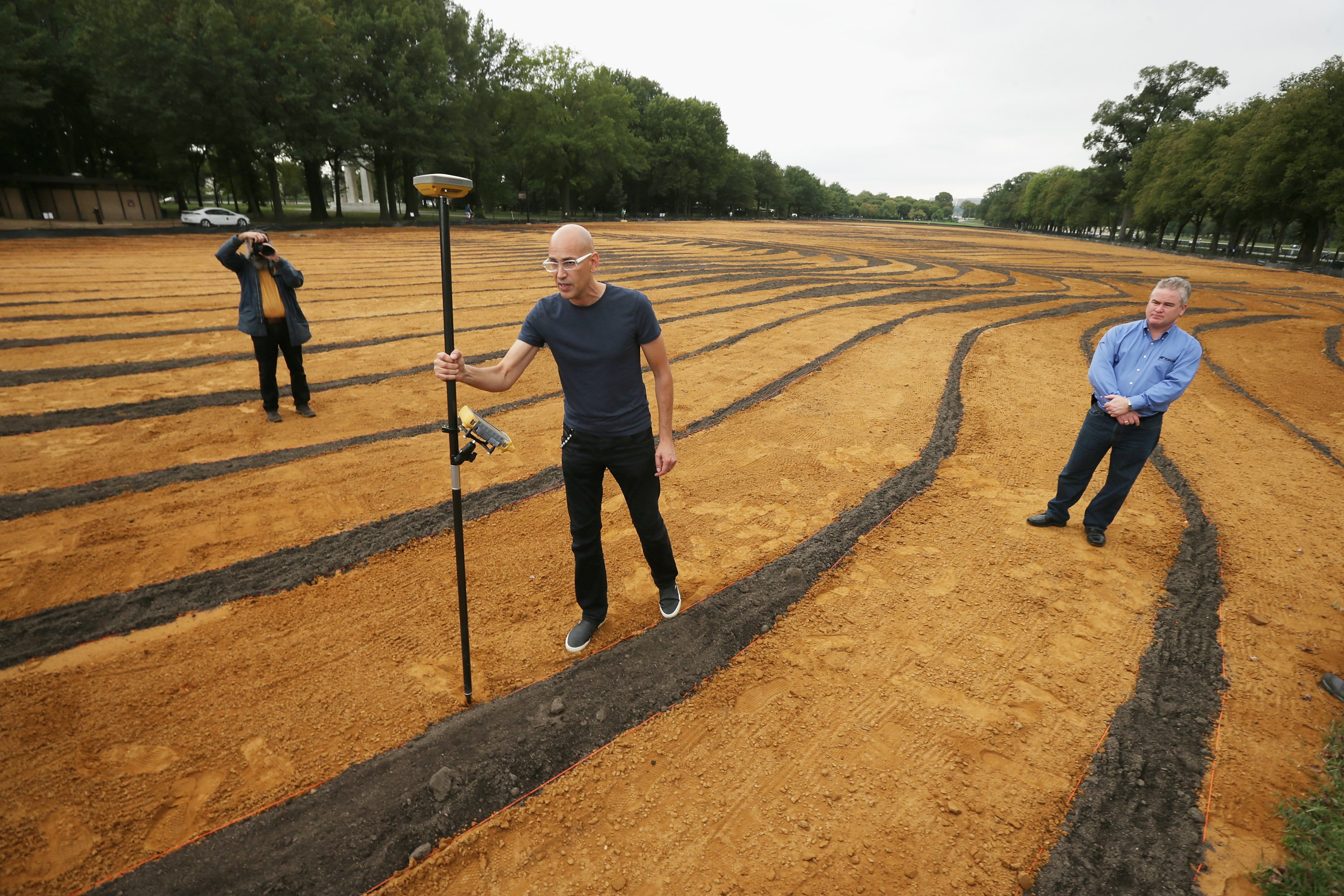 Cuban-American artist Jorge Rodriguez-Gerada demonstrates how a 'rover,' or high-precision GPS marker, was used to create his six-acre sand and soil 'facescape' on the National Mall in Washington, Oct. 1, 2014. (Chip Somodevilla—Getty Images)
