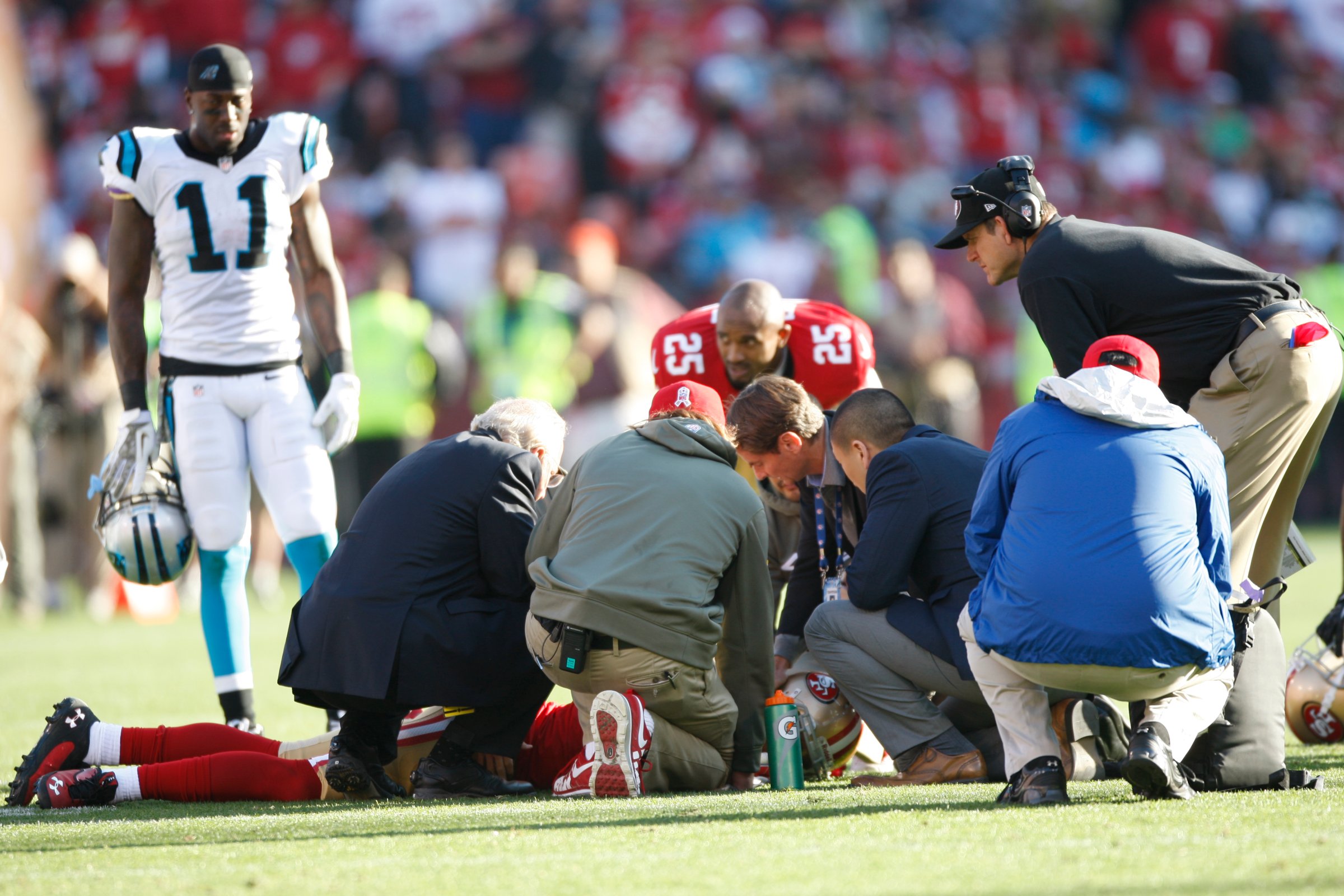 From left: Head Coach Jim Harbaugh of the San Francisco 49ers and the medical staff check out Eric Reid after he received a concussion during the game against the Carolina Panthers on November 10, 2013 in San Francisco, California.