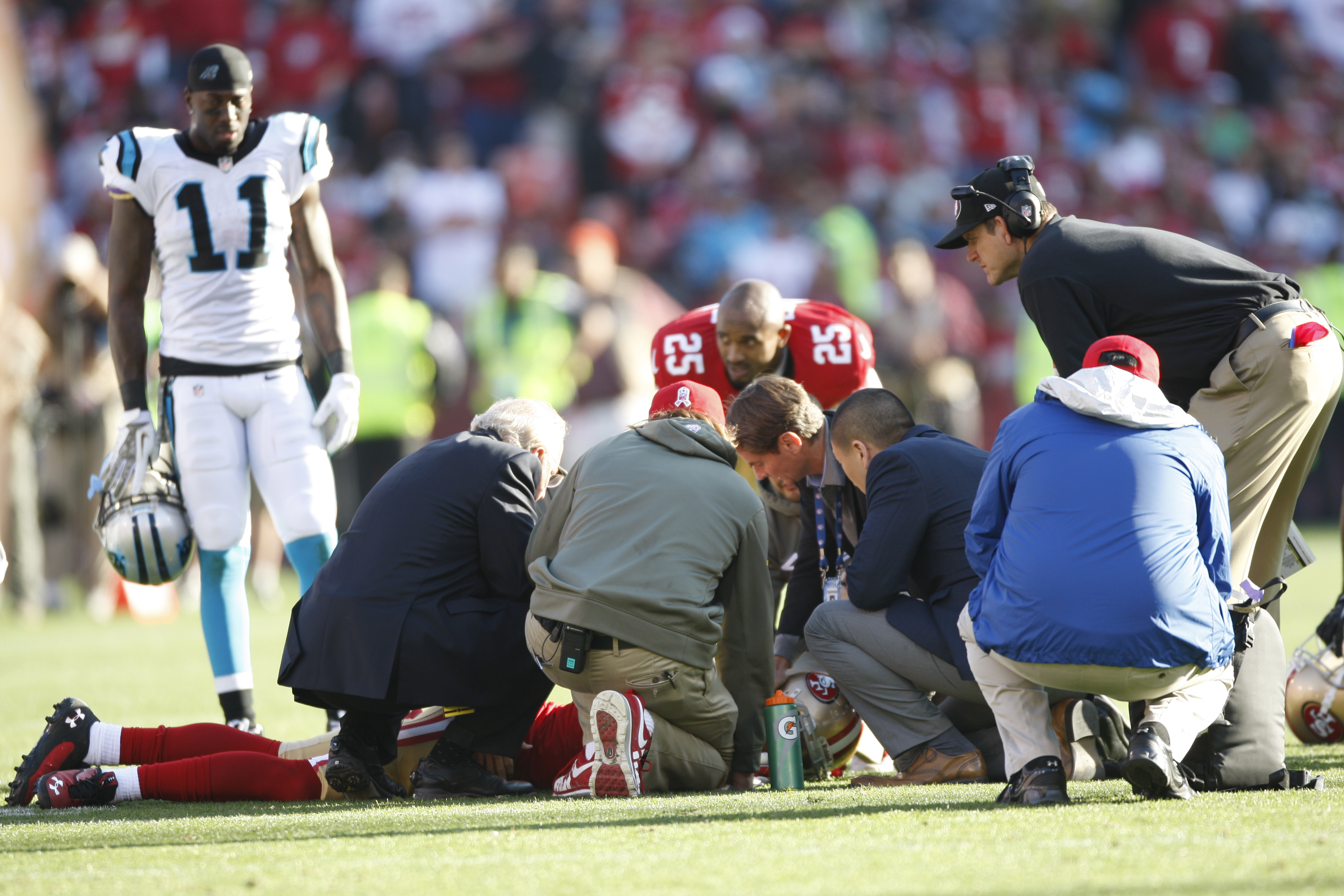 From left: Head Coach Jim Harbaugh of the San Francisco 49ers and the medical staff check out Eric Reid after he received a concussion during the game against the Carolina Panthers on November 10, 2013 in San Francisco, California. (Michael Zagaris—Getty Images)
