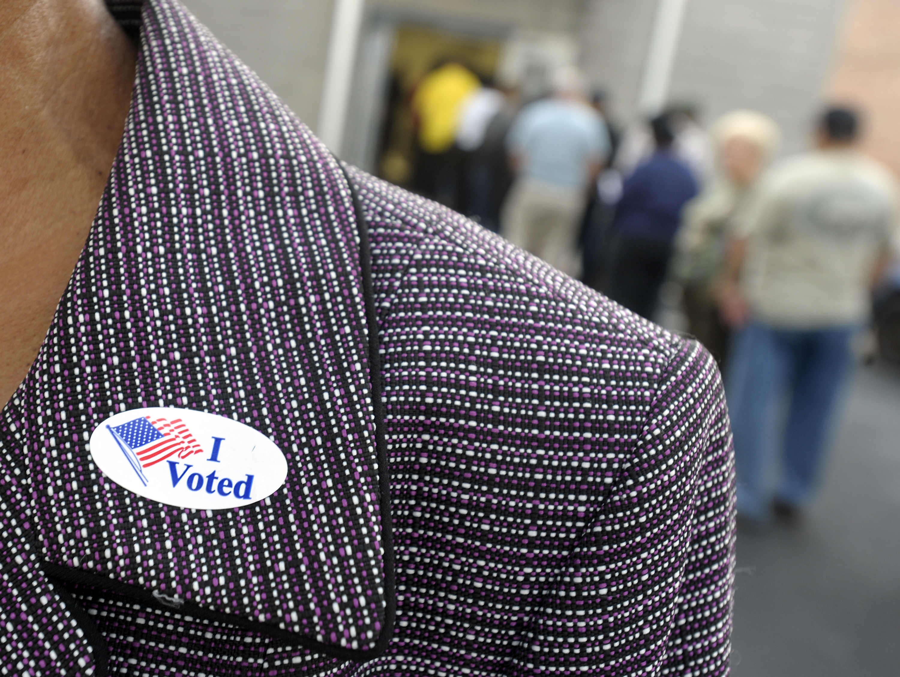 A voter displays an "I Voted" sticker on her lapel after voting as others wait in line for the first day of early voting on Oct. 18, 2012, in Wilson, N.C. (Sara D. Davis—Getty Images)