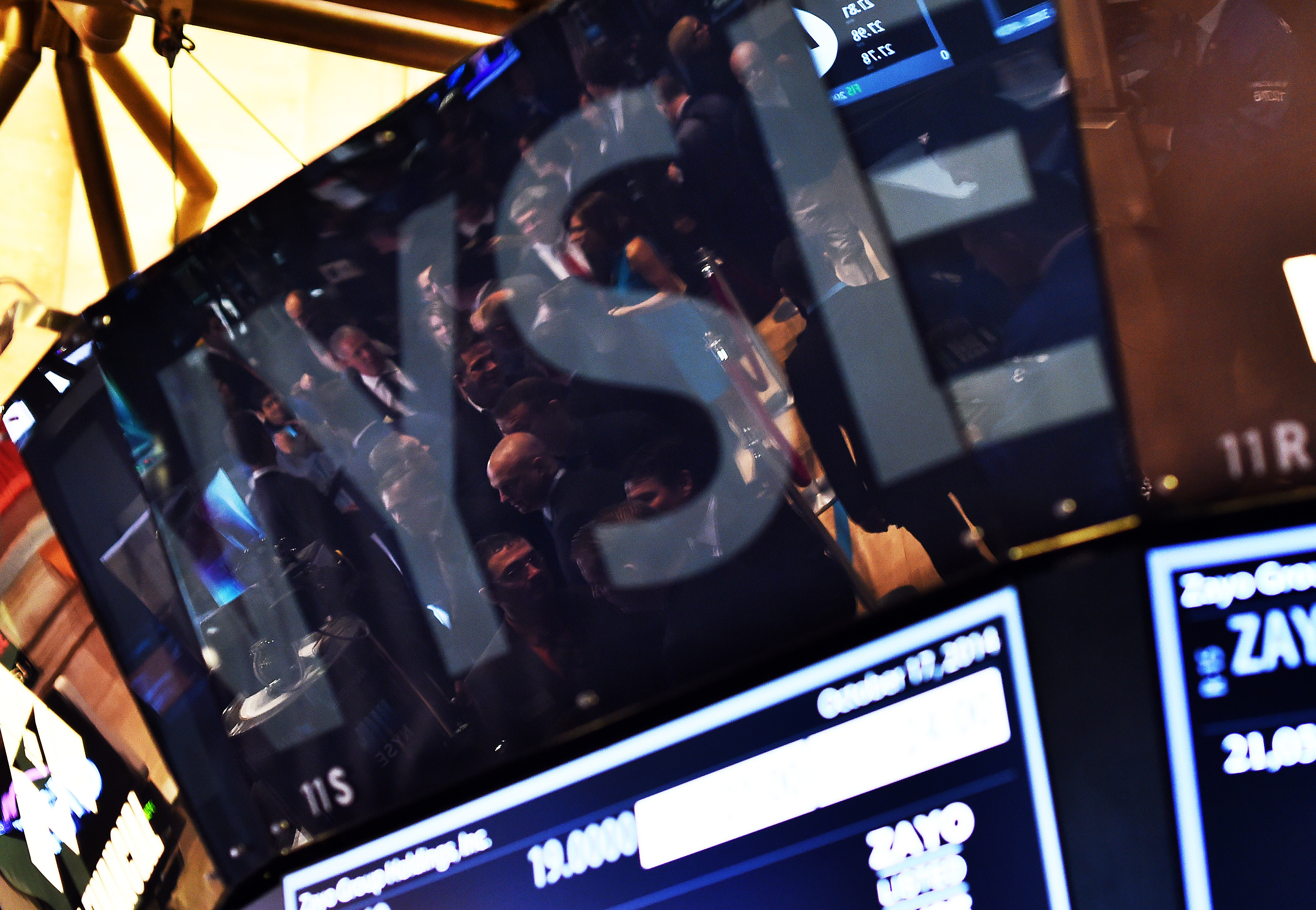 Traders are seen reflected on an electronic display as they work on the floor of the New York Stock Exchange on October 17, 2014 in New York.