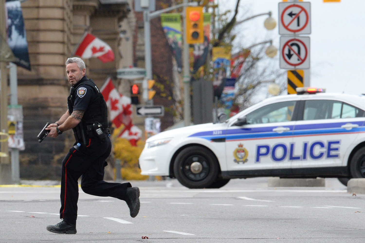 An Ottawa police officer runs with his weapon drawn outside Parliament Hill in Ottawa on Oct. 22, 2014.