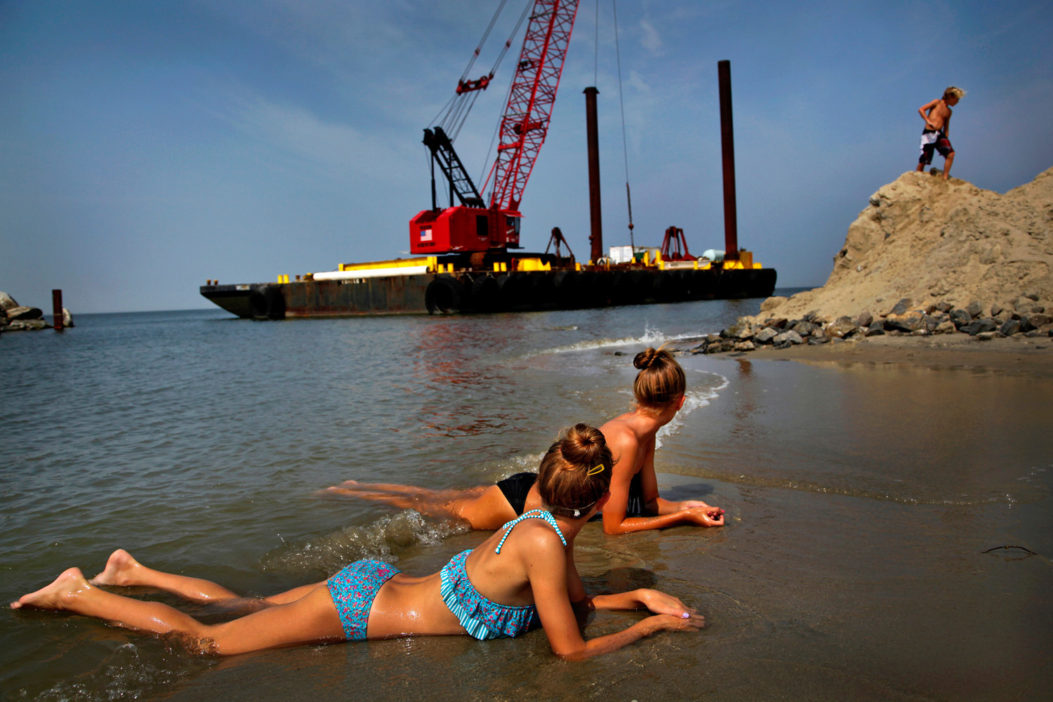 People enjoy the beach next to some heavy equipment in place for jetty construction on Willoughby Spit in Ocean View in Norfolk, Virginia. 2013.