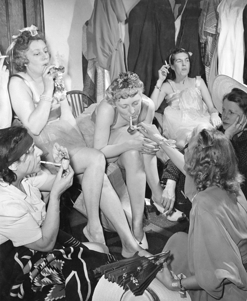 Performers scheduled for later in the evening savor their corncob pipes in a dressing room. LIFE noted the corncobs would likely be a one-time enjoyment: "It wouldn't do in Milford."