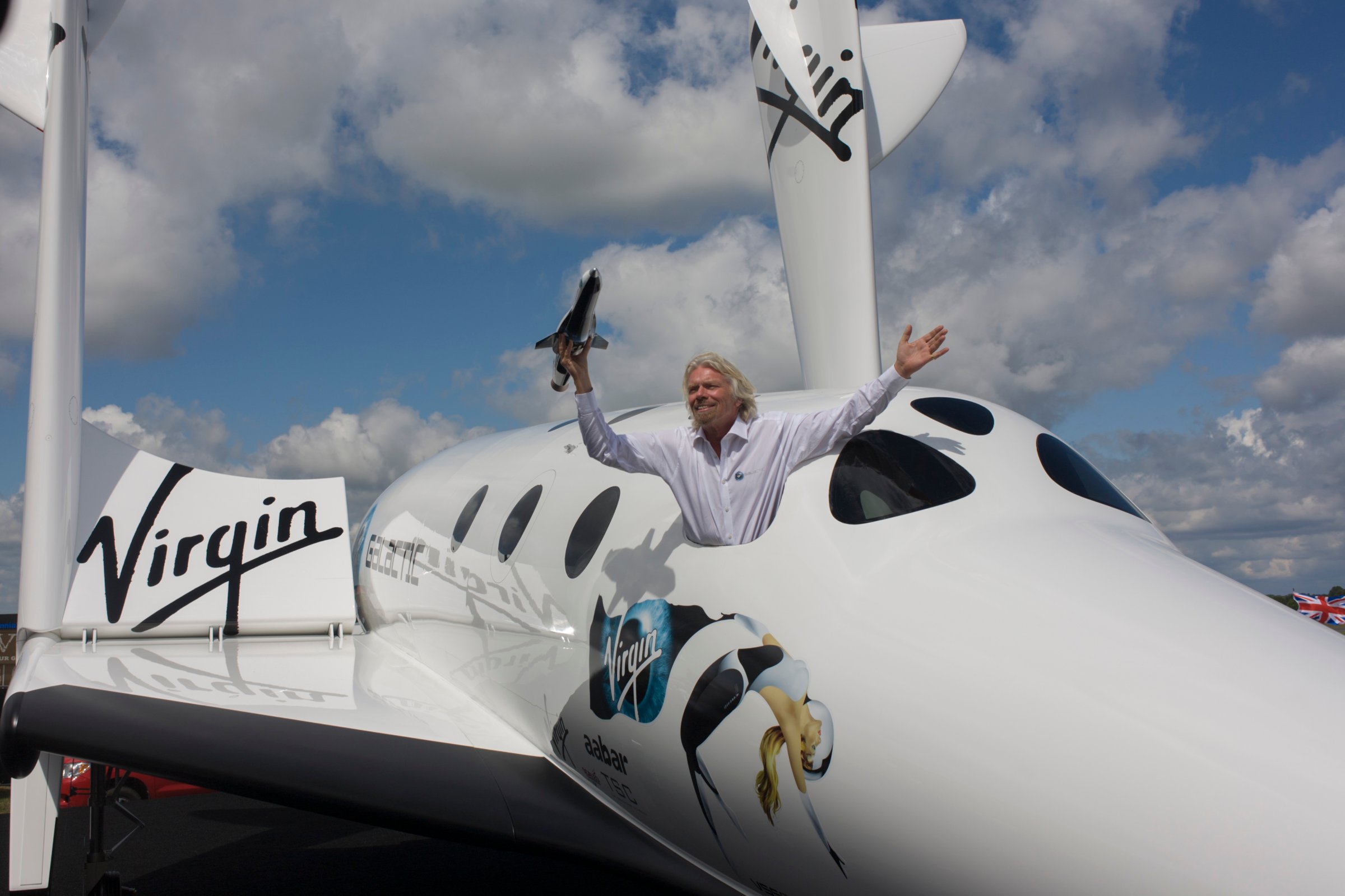 Alongside his SpaceShipTwo vehicle, Richard Branson holds model of satellite LauncherOne after Virgin Galactic space tourism presentation at the 2012 Farnborough Air Show.