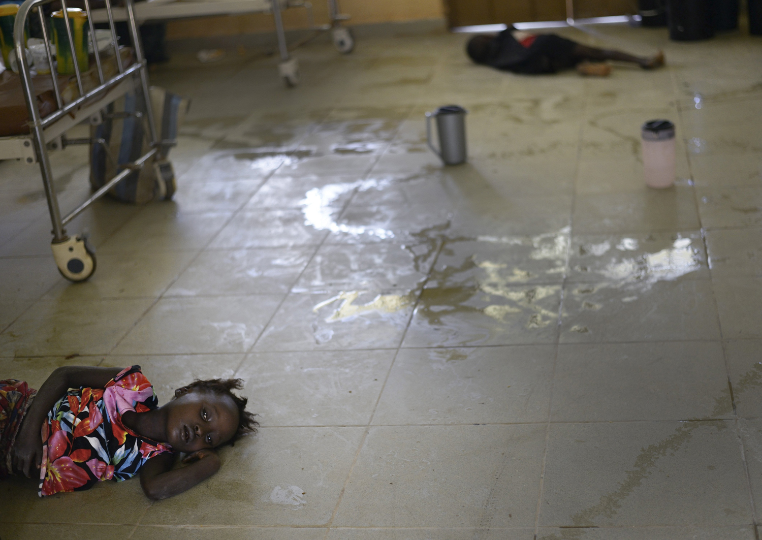 Mariattu Kanu, 4, who is suspected of being infected with Ebola, lies on the floor amid body fluids in a ward for Ebola victims at a hospital in Makeni, Sierra Leone, Sept. 27, 2014.