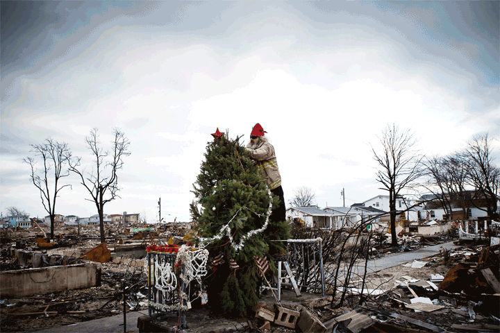 Before: Edward  Roaddawg  Manley, a volunteer at the Point Breeze Volunteer Fire Department, places a star on top of a Christmas tree on Dec. 25, 2012, in Breezy Point, Queens. After: The same section of Breezy Point on Oct. 22, 2013.