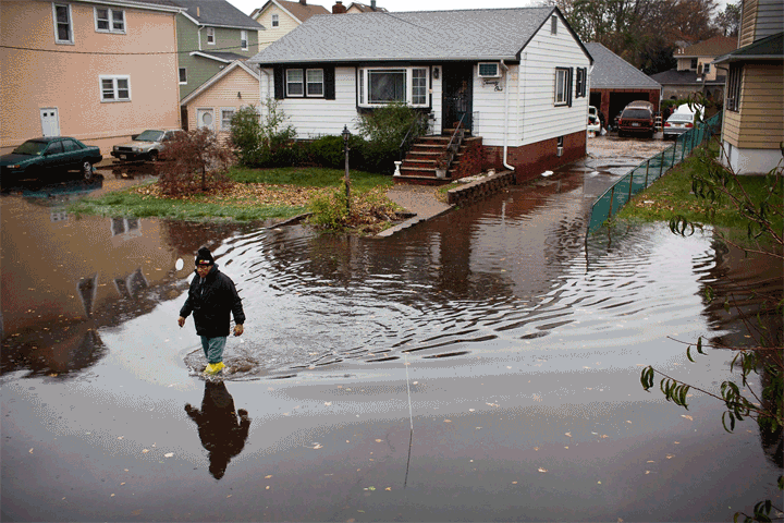 Before: A man walks through a flooded street after Superstorm Sandy, on October 30, 2012, in Little Ferry, New Jersey. After: The same house in Little Ferry on October 22, 2013.