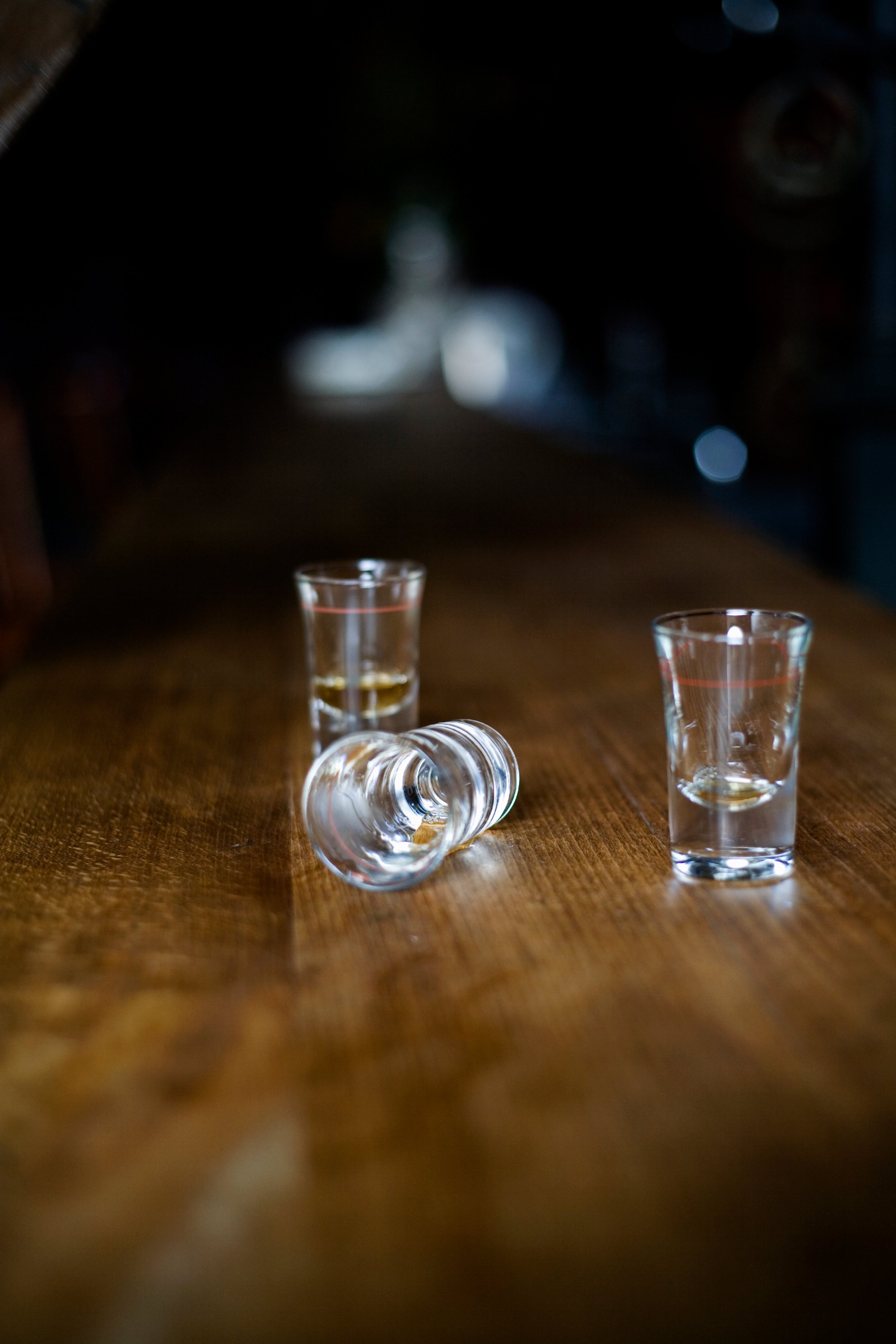 Three empty shot glasses on a bar