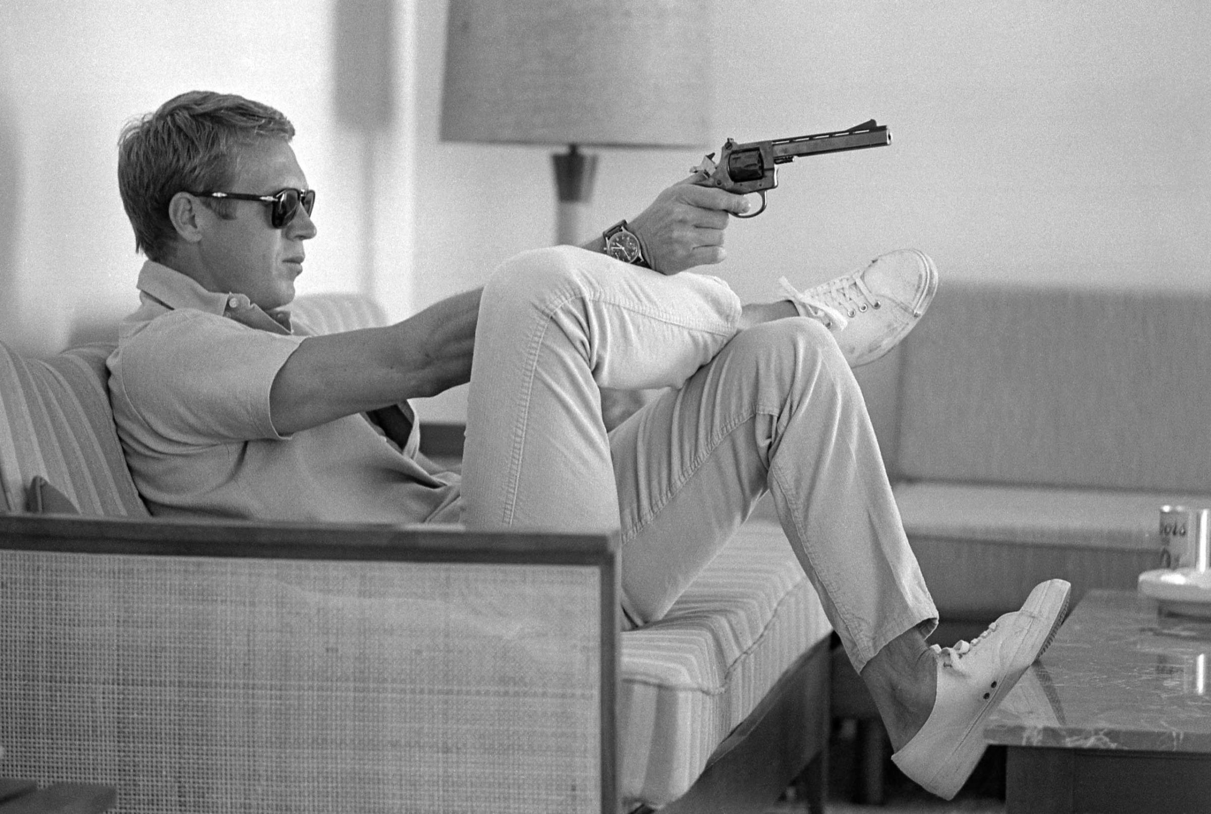 At his bungalow in Palm Springs, Steve McQueen practices his aim before heading out for a shooting session in the desert, 1963.
