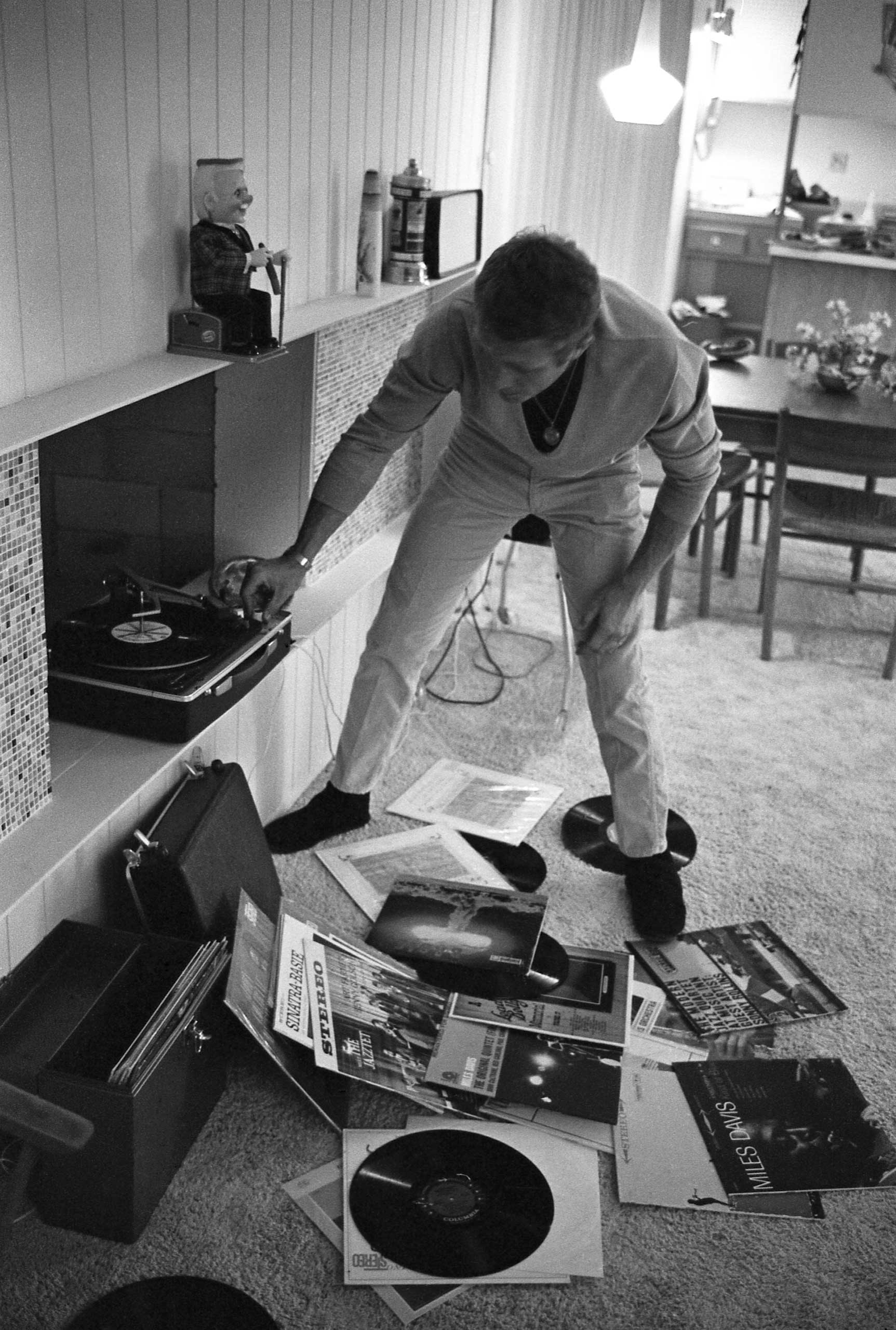 At his Palm Springs bungalow, Steve McQueen puts on a record, with LPs by Miles Davis, Sonny Rollins and Frank Sinatra scattered at his feet, 1963.