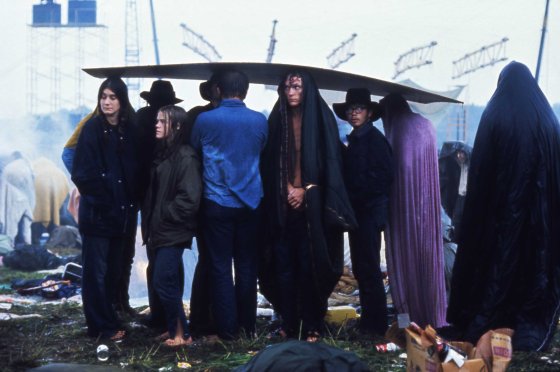 Concert-goers huddle under a sheet of cardboard in the rain at the three-day, era-defining Woodstock Music and Art Fair in Bethel, New York. Originally published in the August 29, 1969, issue of LIFE.