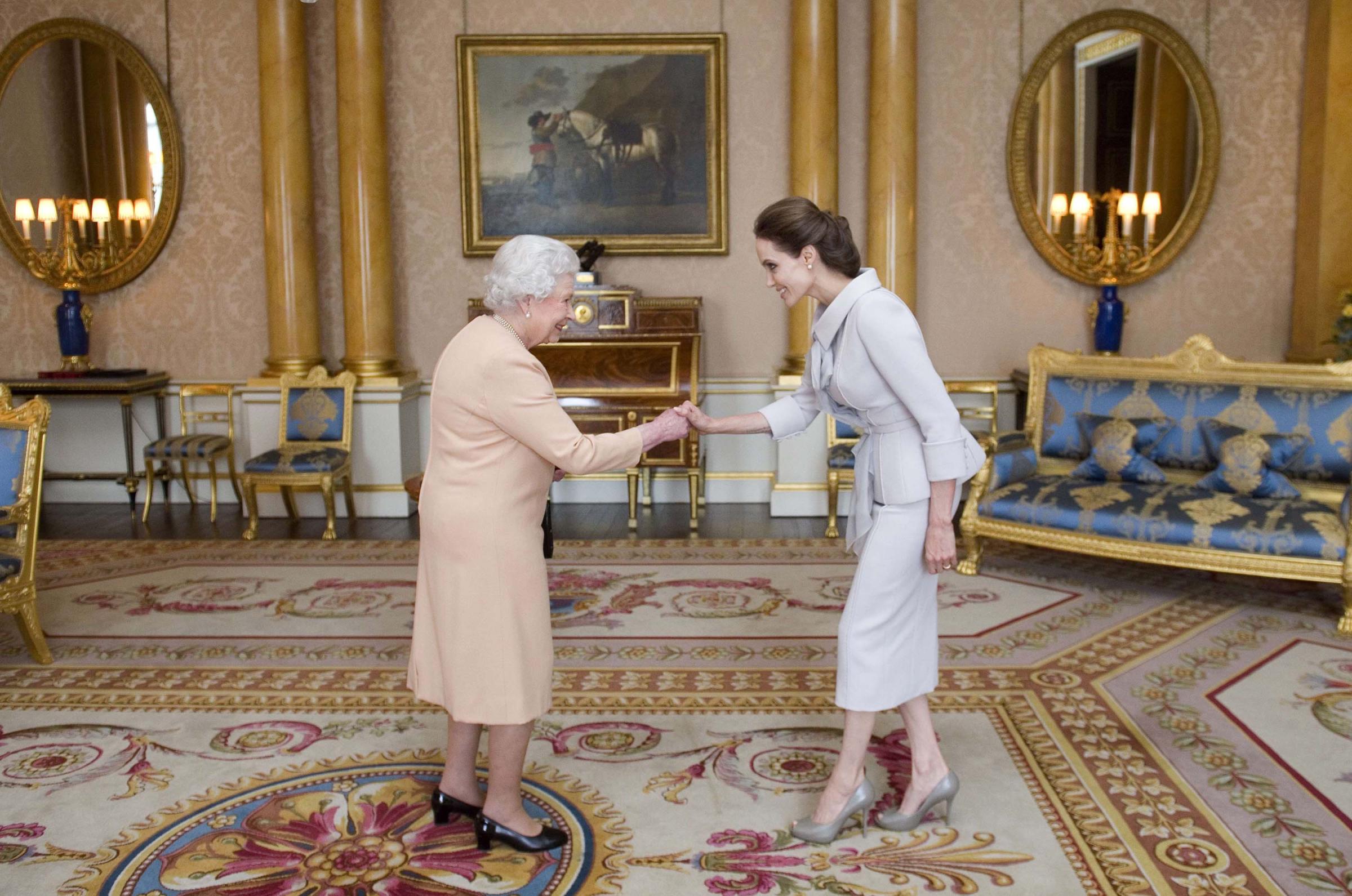 Angelina Jolie is presented with the Insignia of an Honorary Dame Grand Cross of the Most Distinguished Order of St Michael and St George by Britain's Queen Elizabeth II in the 1844 Room at Buckingham Palace in central London, on October 10, 2014.