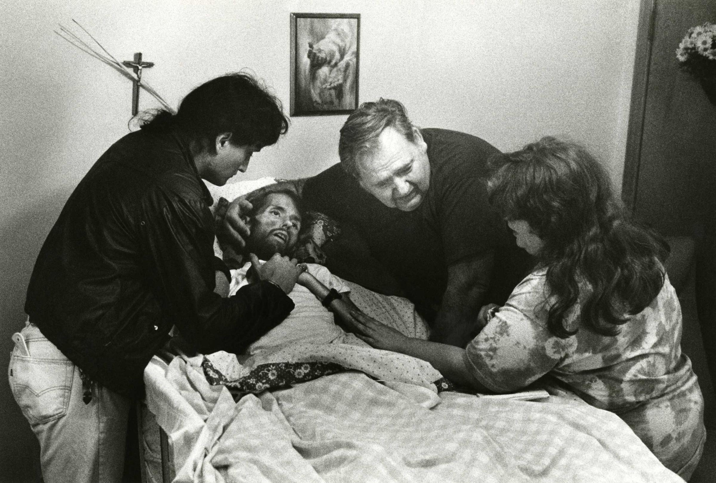 In another of Therese Frare's photos taken in the final moments of David Kirby's life, his caregiver and friend, Peta; David's father; and David's sister, Susan, say goodbye.