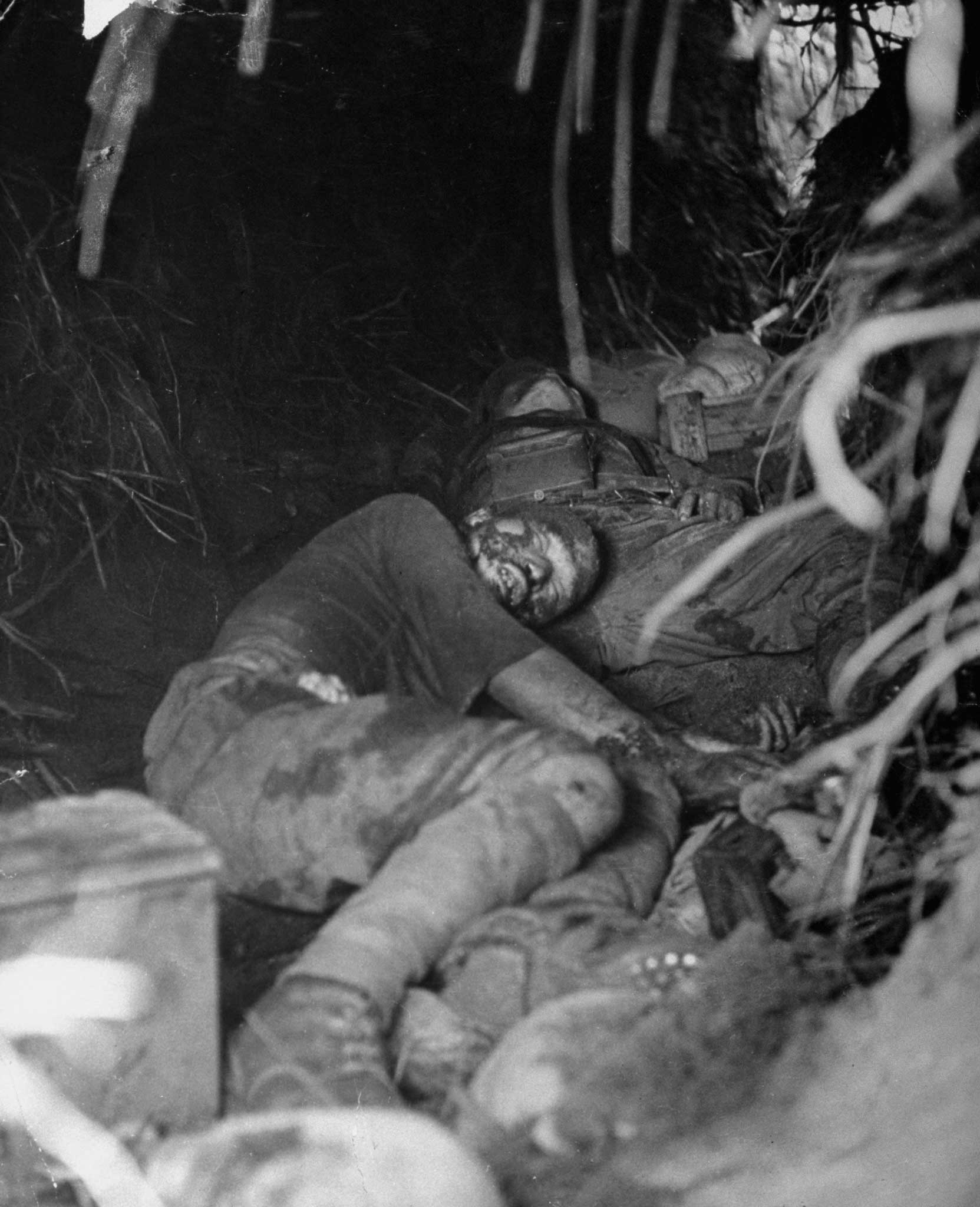"A wounded Jap lies in a destroyed pillbox at Buna Mission. A minute later, he rose up, tried to throw a grenade which he had hidden in his left hand." (Note: The Japanese soldier was shot dead by an American officer who was standing behind Strock.)