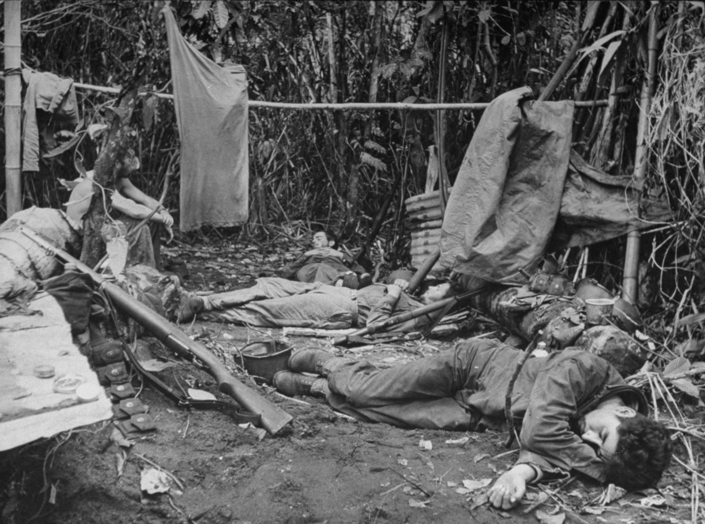 "A few hundred yards behind the lines U.S. soldiers flop in exhaustion, trying to sleep and dry their clothes as best they can."