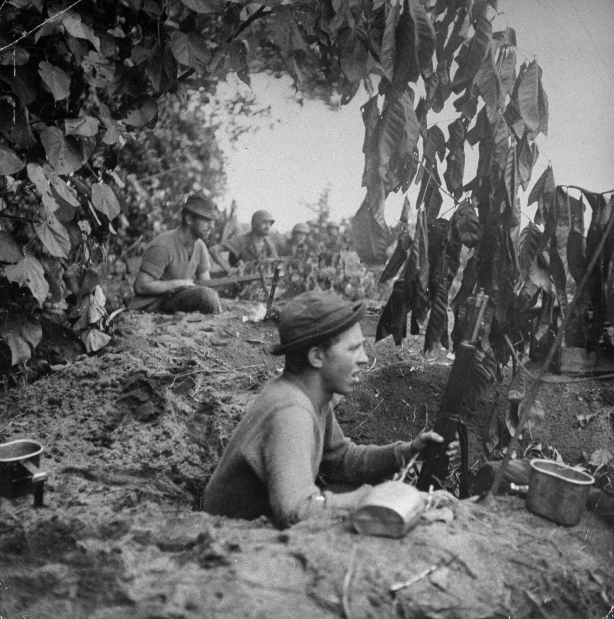 "On Bottcher's Corner men dig into foxholes to support machine-gun positions directly ahead of them. From the end of the corridor carved out by Bottcher's men between Buna Village and Buna Mission. A minute later one of these men was wounded."