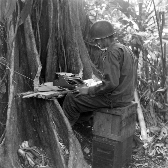 Typing at an improvised table, Buna, New Guinea Campaign, WWII.