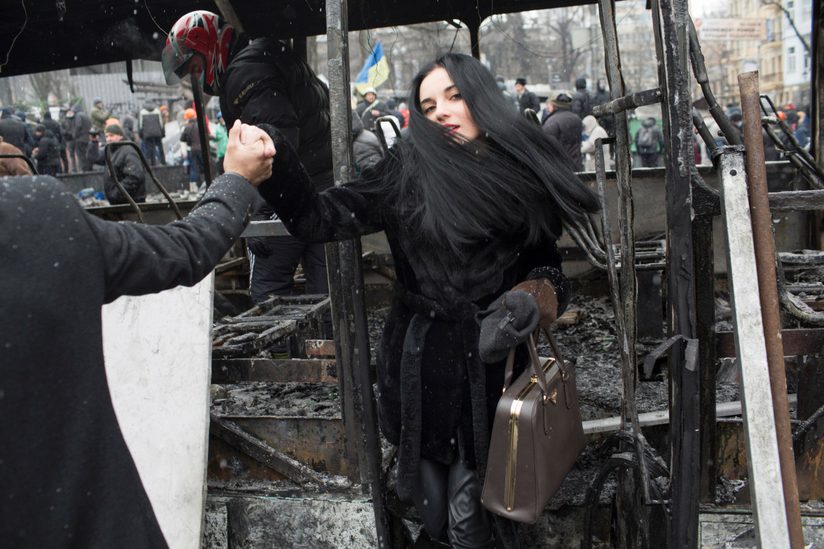 A young woman steps off a destroyed vehicle that was used to form a barricade during a lull in violent clashes between demonstrators and police forces on Hrushevsky Street in central Kyiv. January 21, 2014