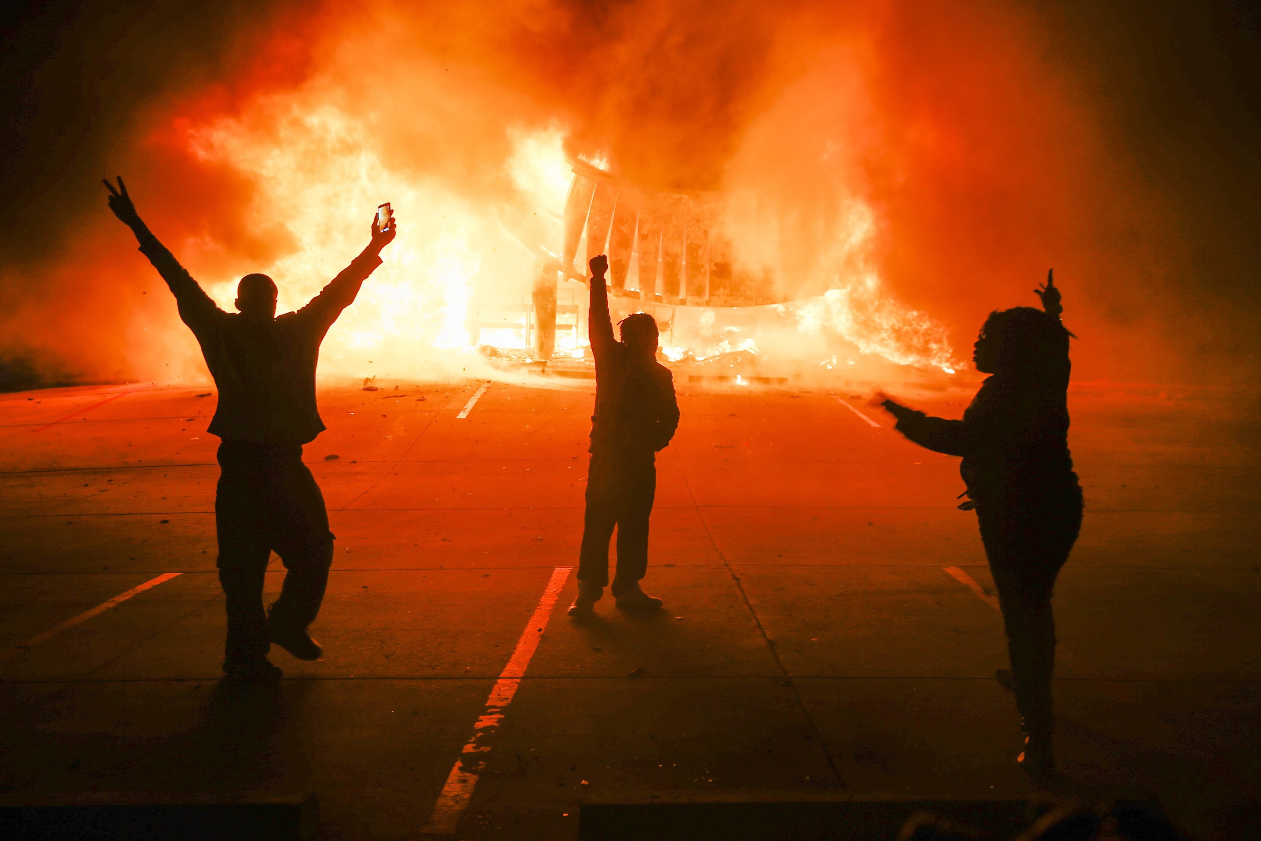 Protestors parade in the parking lot of a burning auto parts store in Ferguson, Mo. on Nov. 24, 2014.
