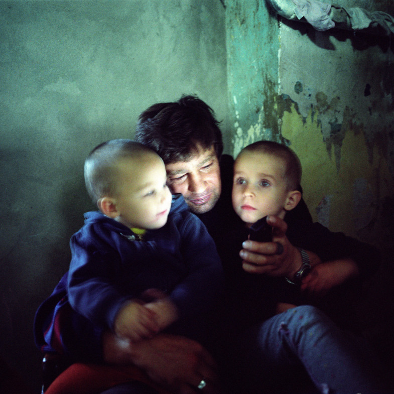 Sasha, who is HIV-positive, watches a video on his mobile phone with his child and grandson. Odesa, Ukraine, 2008