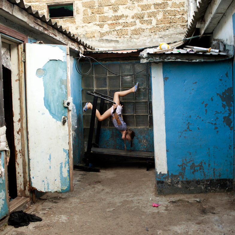 Masha, who recently turned 11 years old, plays in the small courtyard to her home. Odesa, Ukraine, 2012