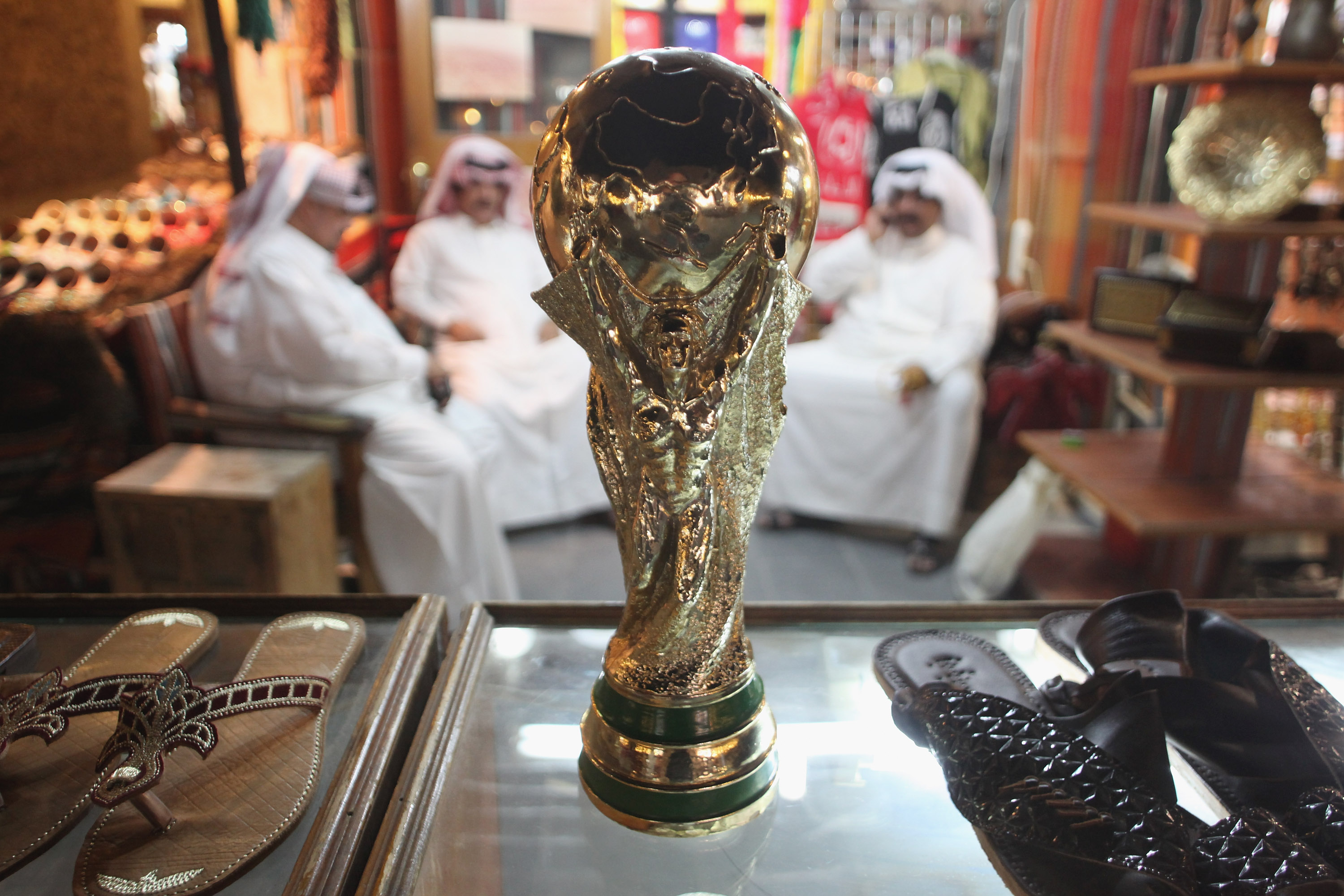 DOHA, QATAR - OCTOBER 24:  Arab men sit at a shoemaker's stall with a replica of the FIFA World Cup trophy in the Souq Waqif traditional market on October 24, 2011 in Doha, Qatar. Qatar will host the 2022 FIFA World Cup football competition and is slated to tackle a variety of infrastructure projects, including the construction of new stadiums.  (Photo by Sean Gallup/Getty Images) (Sean Gallup/Getty Images)