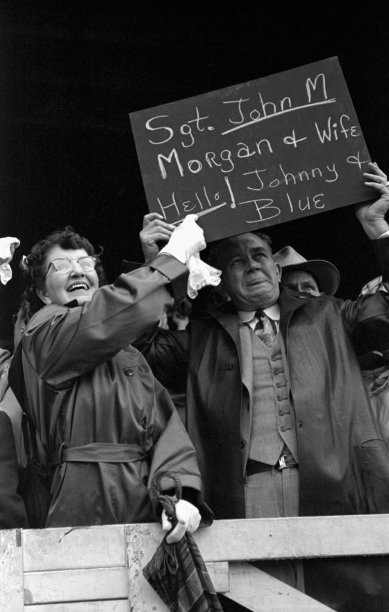 Johnie's parents wave a sign with Johnie's name misspelled. Father, who works in Navy Yard, took day off to greet Johnie and Blue.