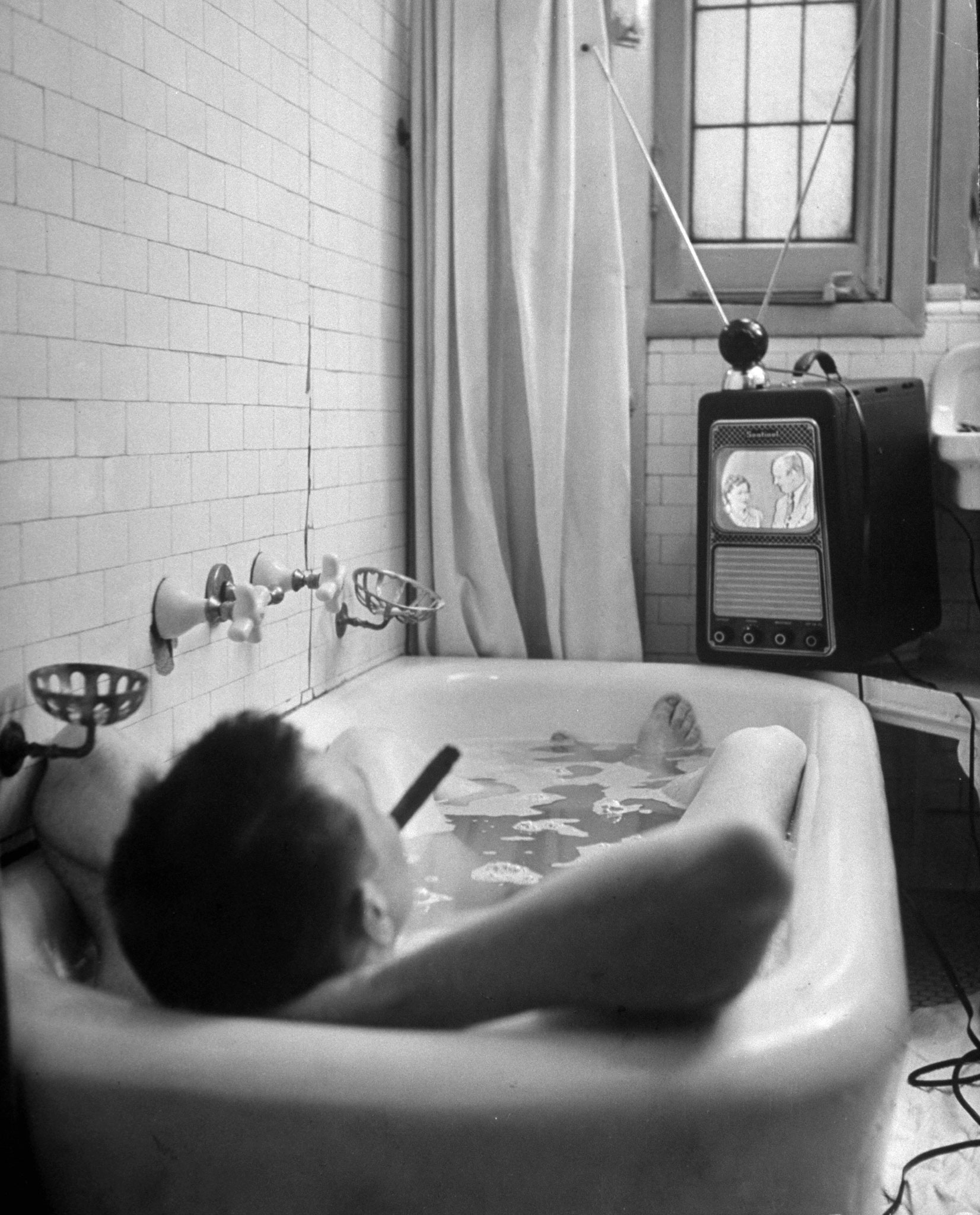 Writer Russell Finch enjoys a smoke, a bath and a TV show in 1948