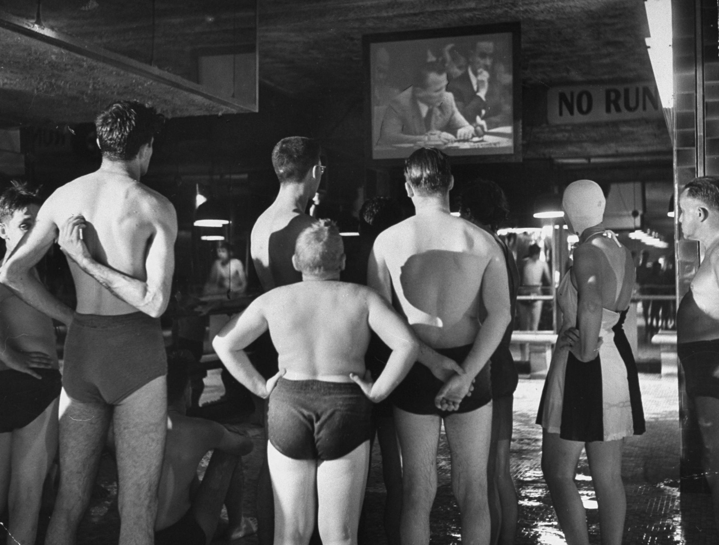 A group of swimmers at an indoor pool watch the Russian ambassador to the United Nations, Jacob Malik, filibustering in the UN Security Council in 1950.
