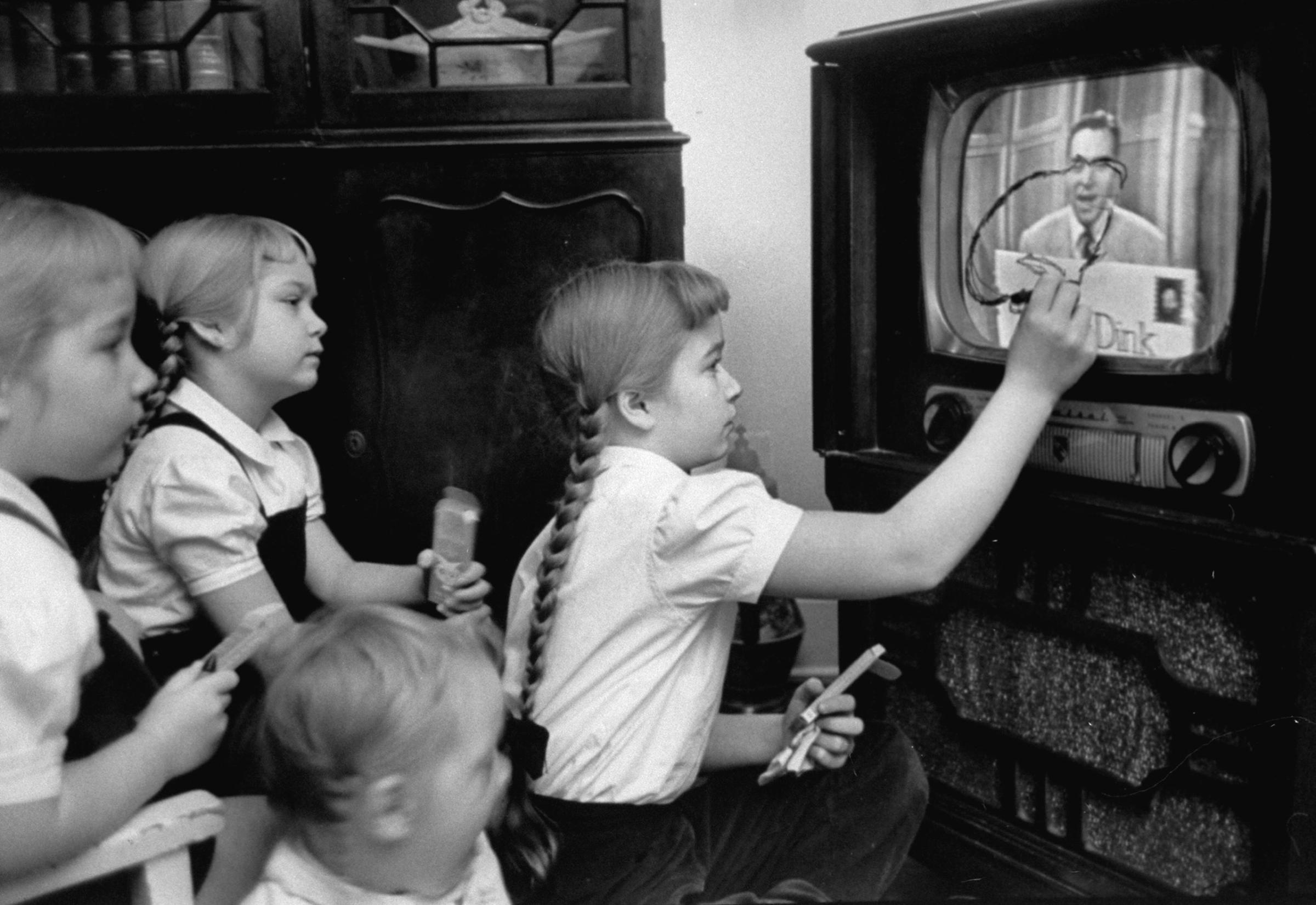 Six-year-old girls use a "Winky Dink" drawing kit on their home TV screen as they watch the kids' program, 1953. The show, which aired for four years in the 1950s, has been cited as "the first interactive TV show," especially in light of its "magic drawing screen" — a piece of plastic that stuck to the TV screen, and on which kids (and, no doubt, some adults) would trace the action on the screen.