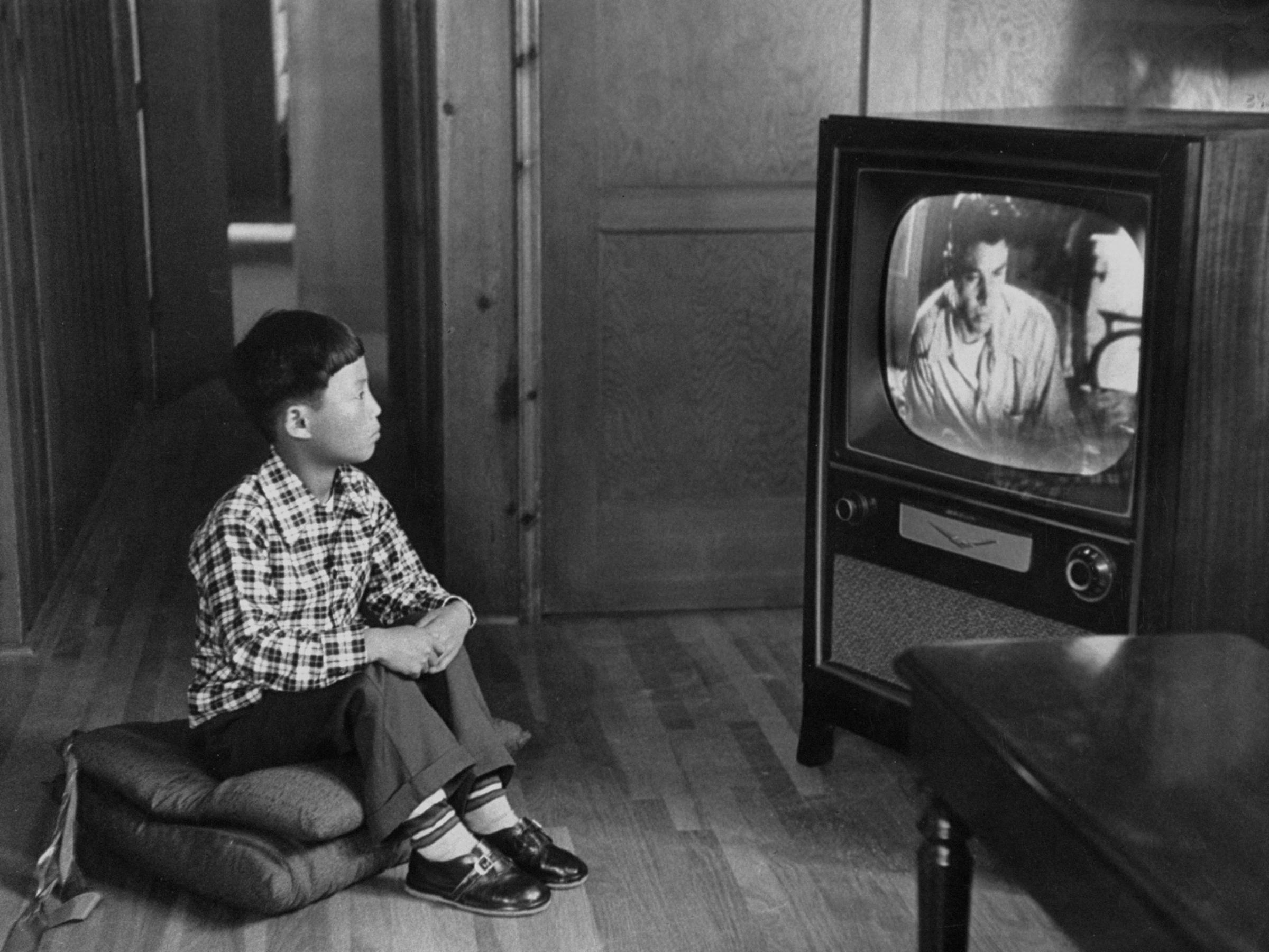 An adopted Korean war orphan, Kang Koo Ri, watches television in his new home in Los Angeles in 1956.