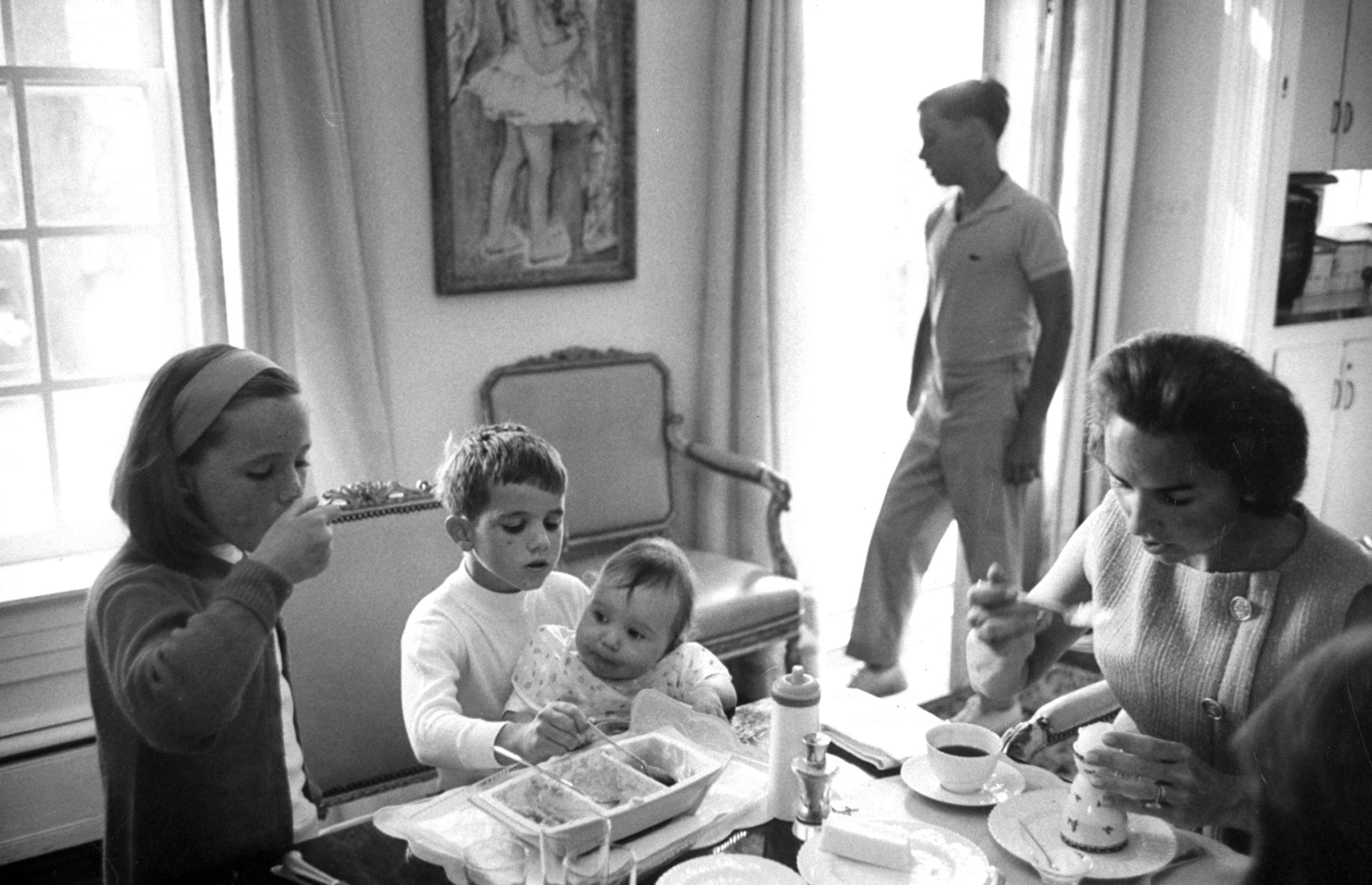 Ethel finishes her meal as Michael, 6, holds Christopher, one, in lap and 7-year-old Courtney tempts baby by testing his food. Joseph, 11, looks out window.