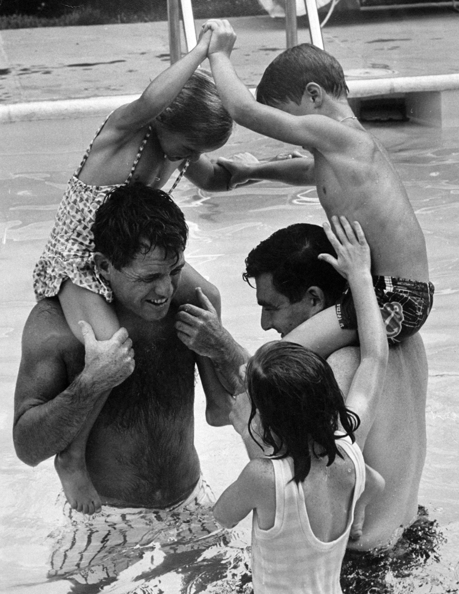 Robert Kennedy and Pierre Salinger joust with kids in Kennedy's pool, 1964.