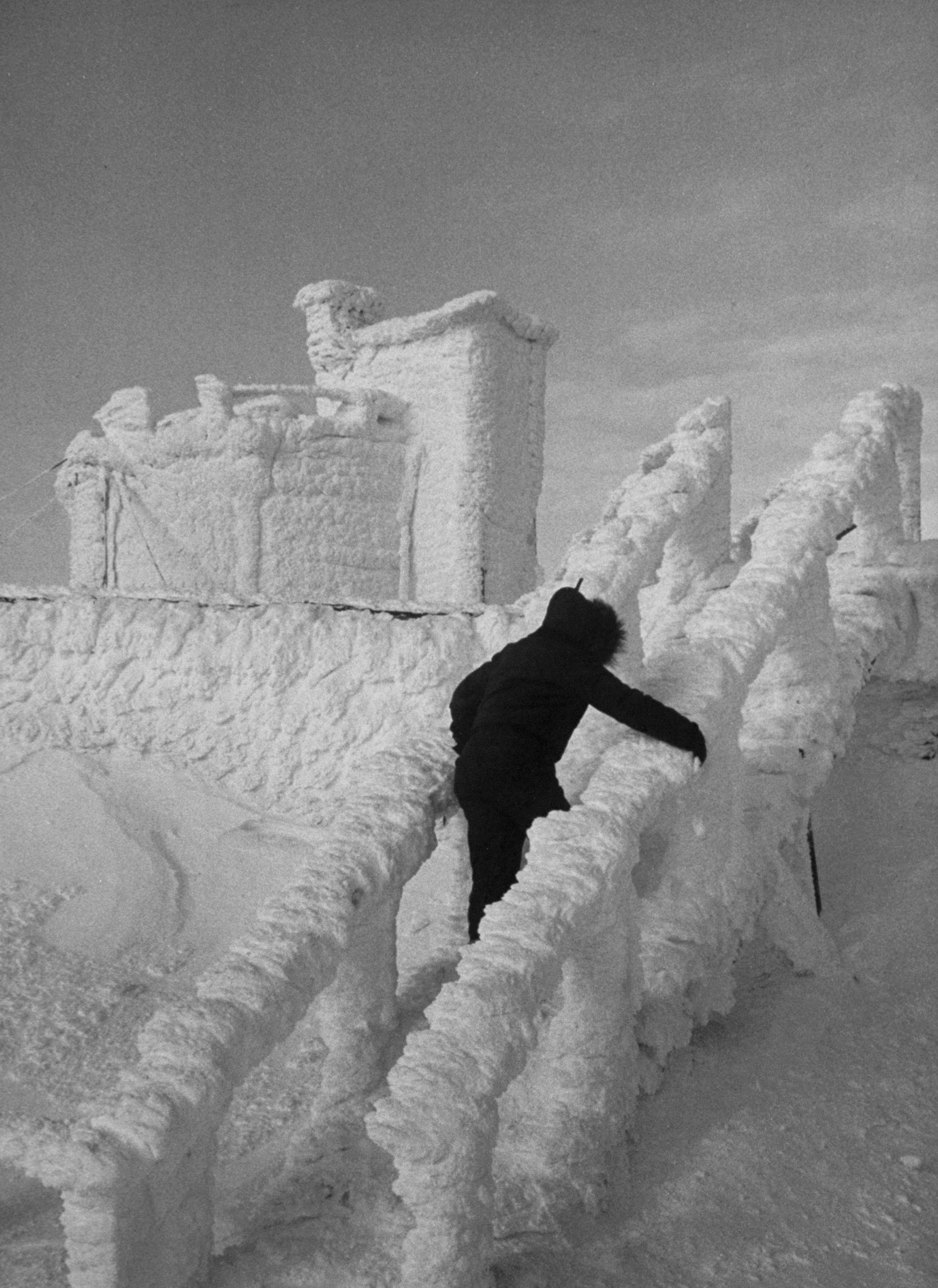 A technician clambers around Summertime Hotel which, in dead of winter, stands castle-like and forbidding, its doors and windows sealed with foot of ice.