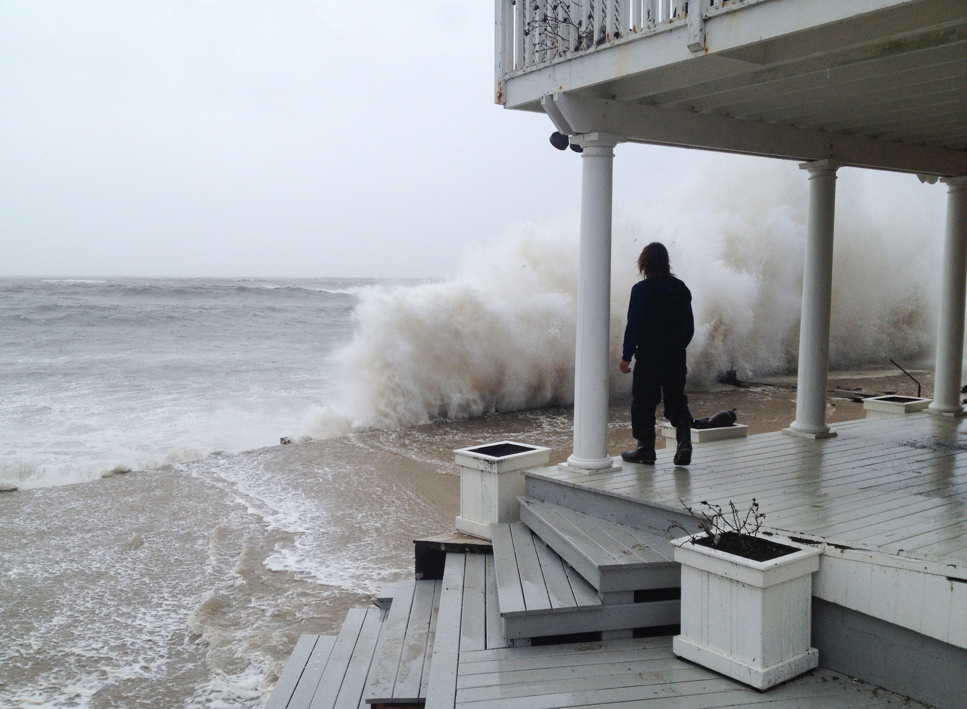 A wave crashes against the shore while person stands on a porch as Hurricane Sandy moves up the coast October 29, 2012 in Montauk, New York. (Sheila Rooney&mdash;Getty Images)
