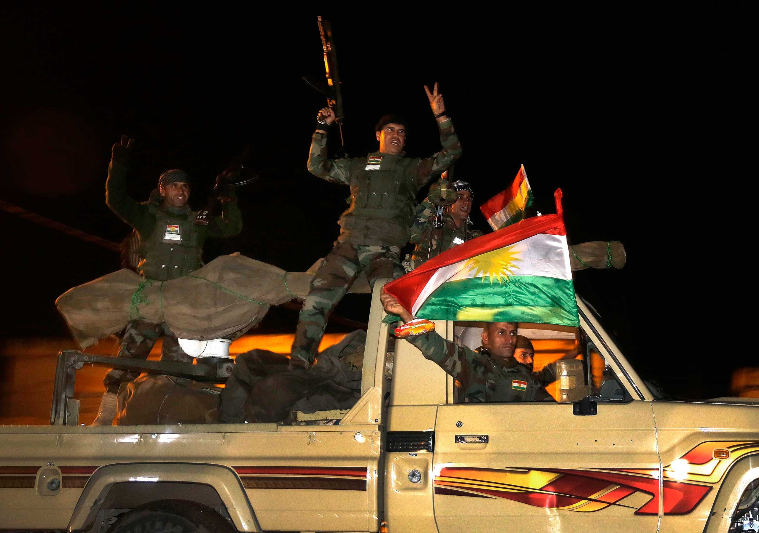 Kurdish peshmerga fighters wave Kurdish flags atop an army vehicle as they move towards the Syrian town of Kobani  from the border town of Suruc, Sanliurfa province, Oct. 31, 2014. (Yannis Behrakis—Reuters)