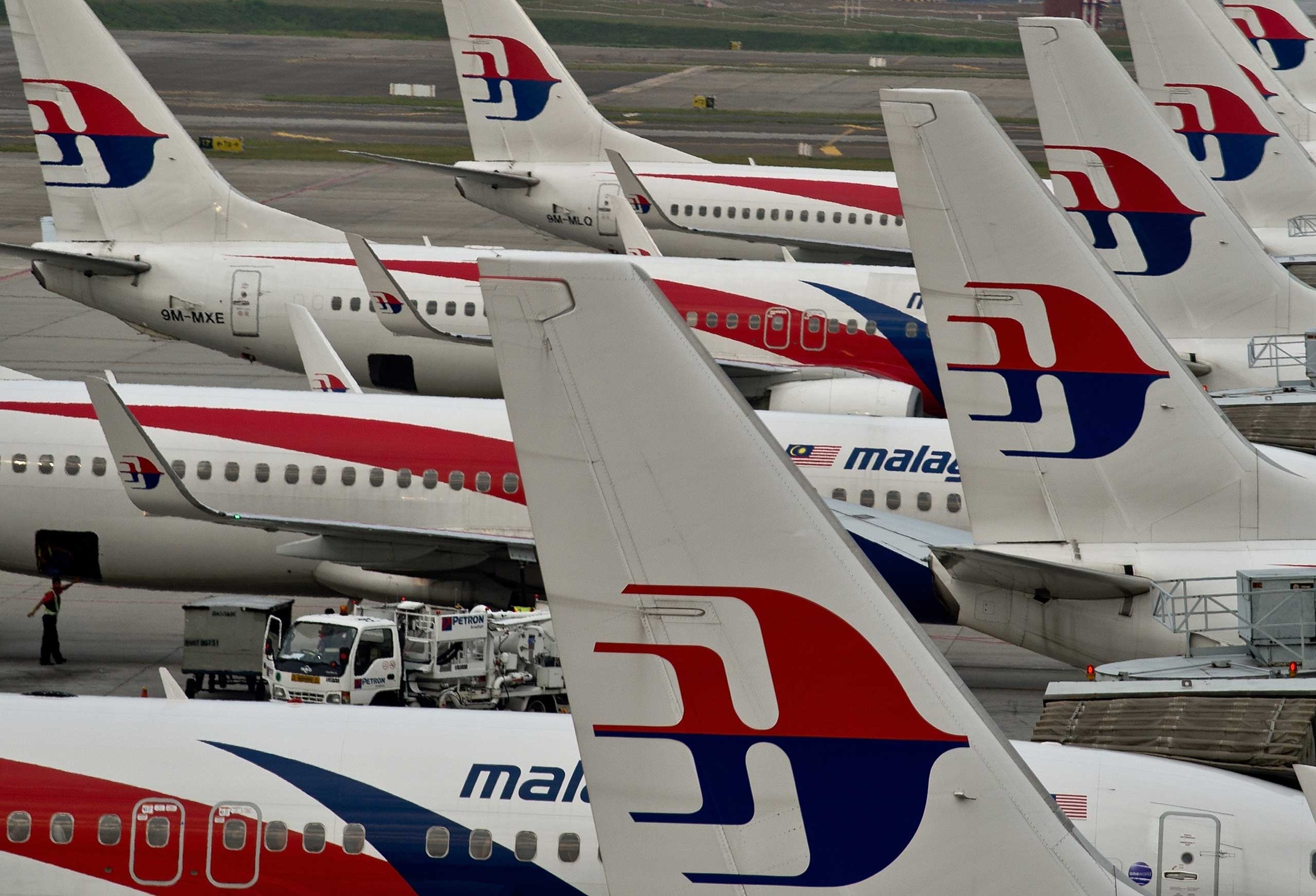 Airport groundstaff walk past Malaysia Airlines planes parked on the tarmac at the Kuala Lumpur International Airport in Sepang on June 17, 2014. (Manan Vatsyana—AFP/Getty Images)