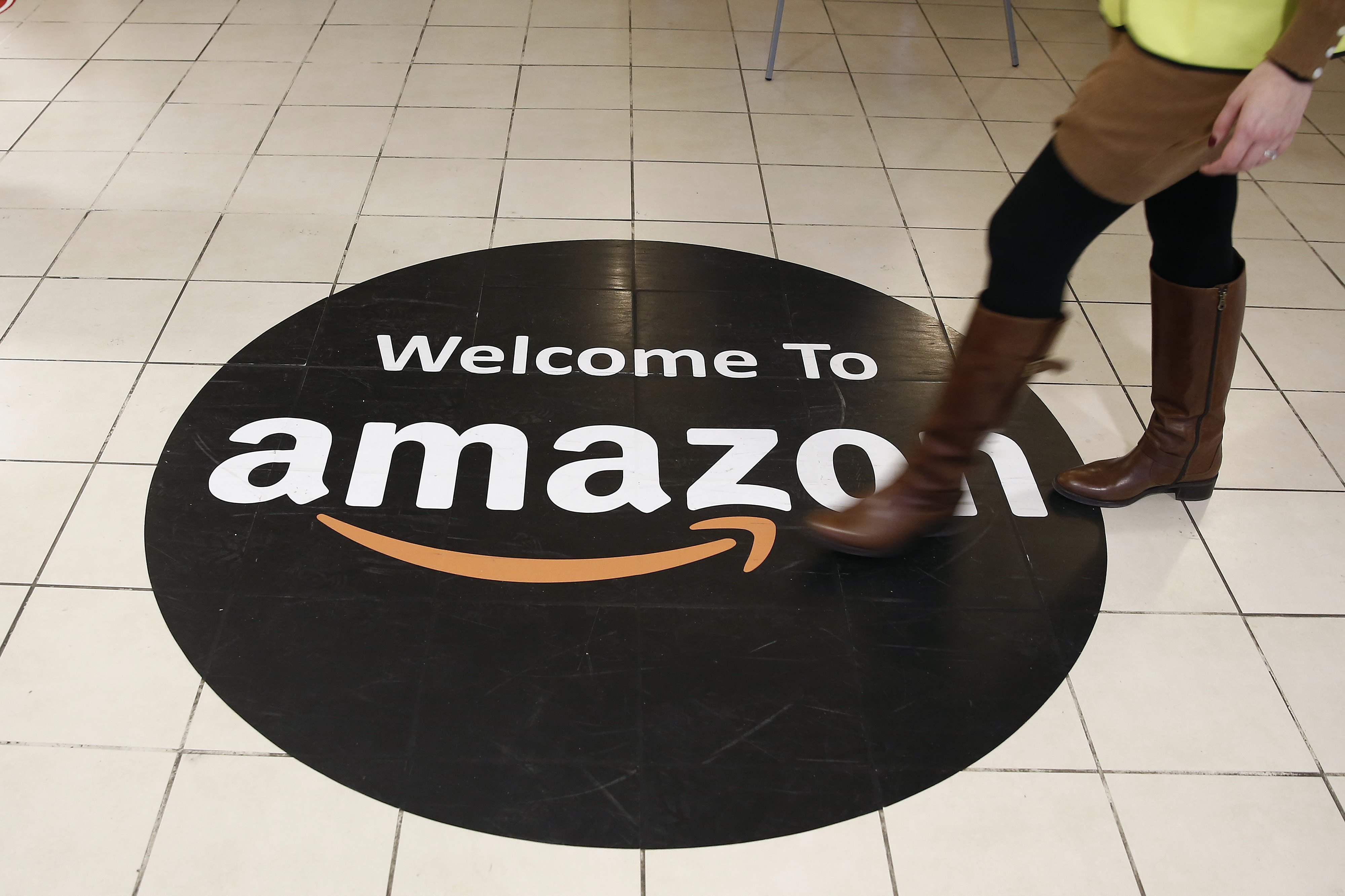 An employee walks over a logo on the floor of Amazon.com Inc.'s fulfillment centers in Rugeley, U.K. on Dec. 2, 2013. (Simon Dawson—Bloomberg/Getty Images)