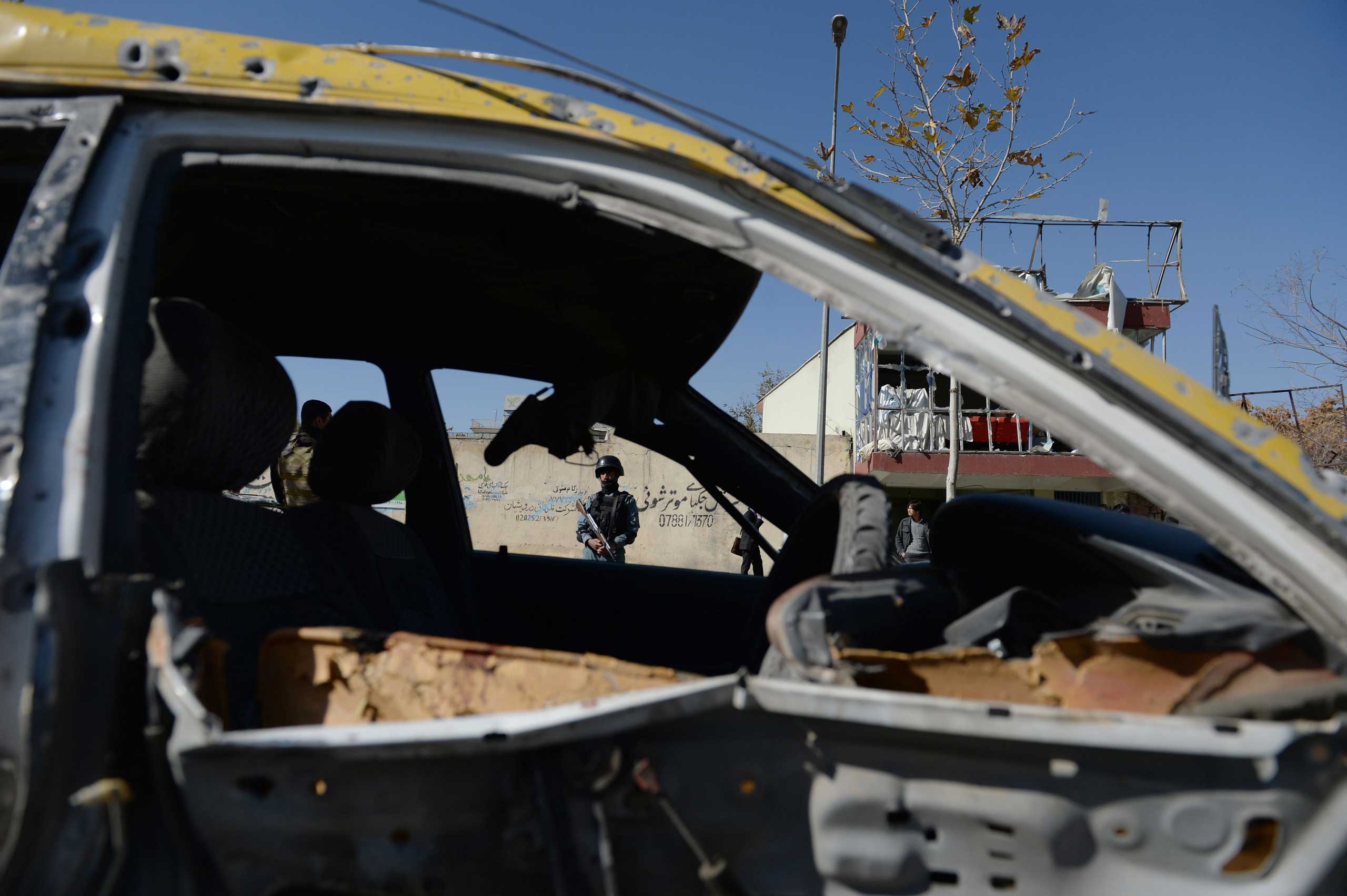 An Afghan policeman is seen through the wreckage of a taxi which was destroyed by a suicide attack targeting a vehicle convoy of Afghan lawmakers in Kabul, Afghanistan on Nov. 16, 2014. (Farshad Usyan—AFP/Getty Images)