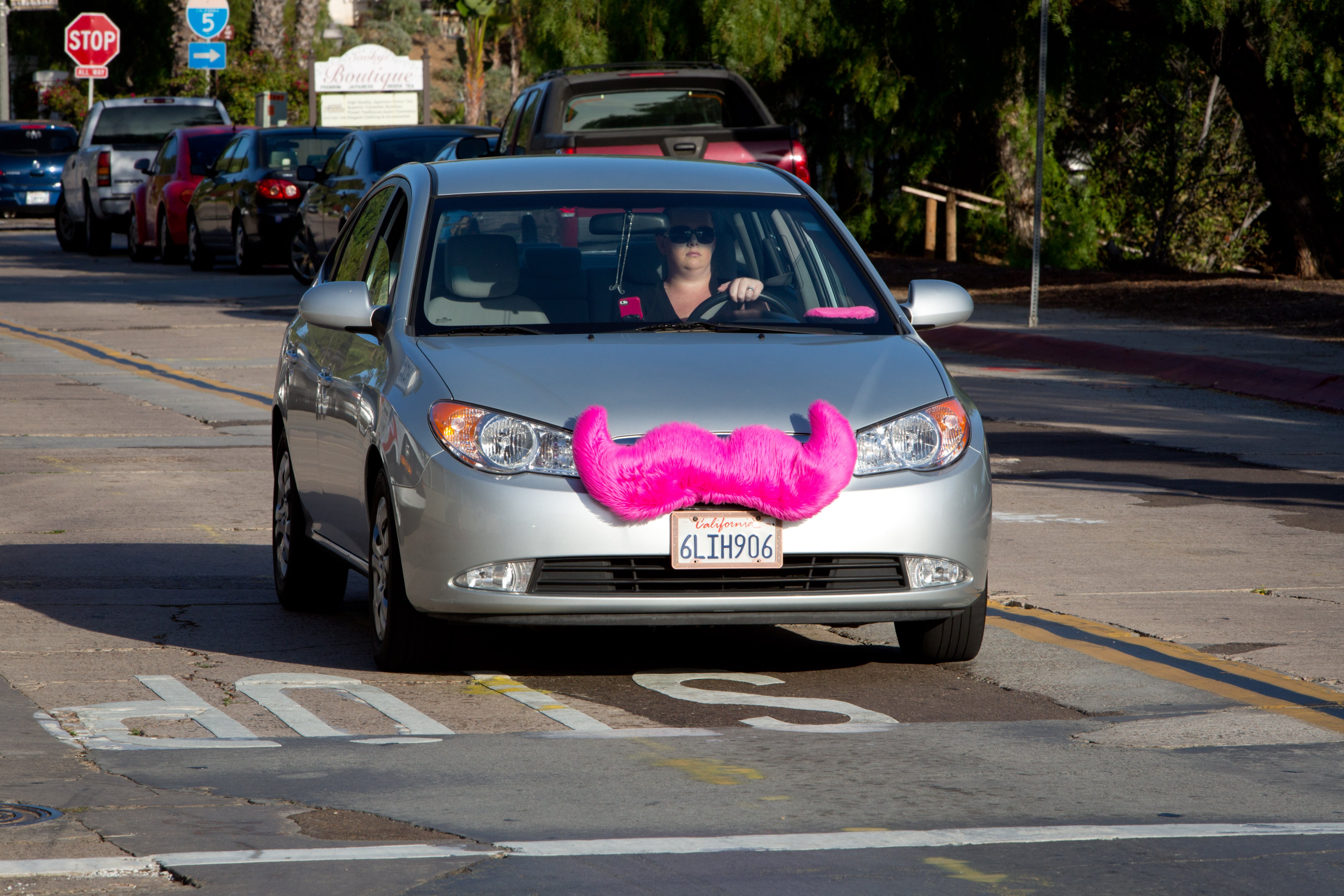 A woman is driving a car for the rideshare company Lyft with a fake jumbo pink mustache that attaches to the grille of the car, in June 2014. (Frank Duenzl/picture-alliance/dpa/AP Images)
