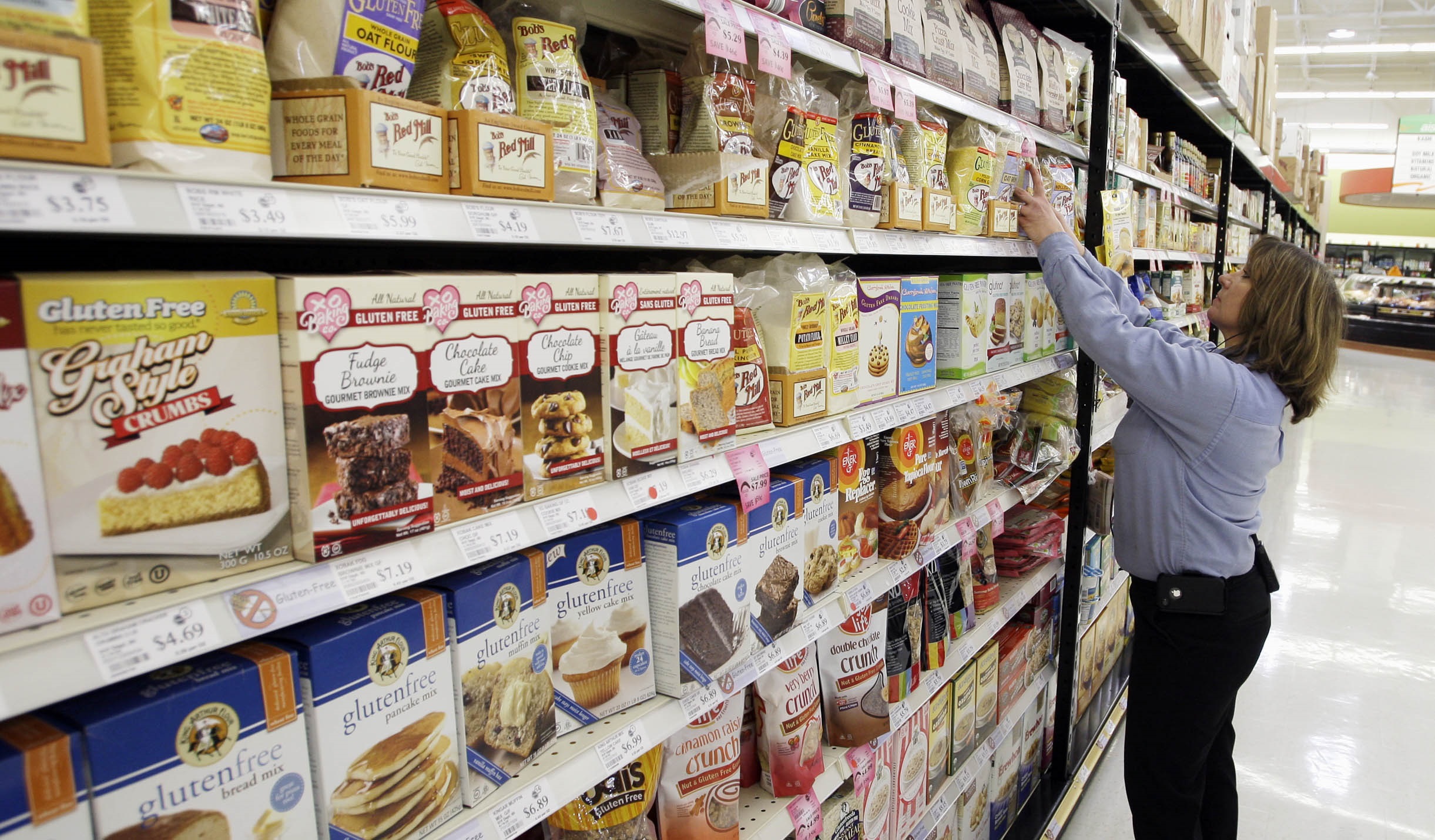 In this Saturday Nov. 23, 2013 photo, Laura Hoffmann, shift manager at Festival Foods in Sheboygan, Wis., makes sure the gluten free products are in their proper spot on the shelves. (Gary C. Klein — AP)