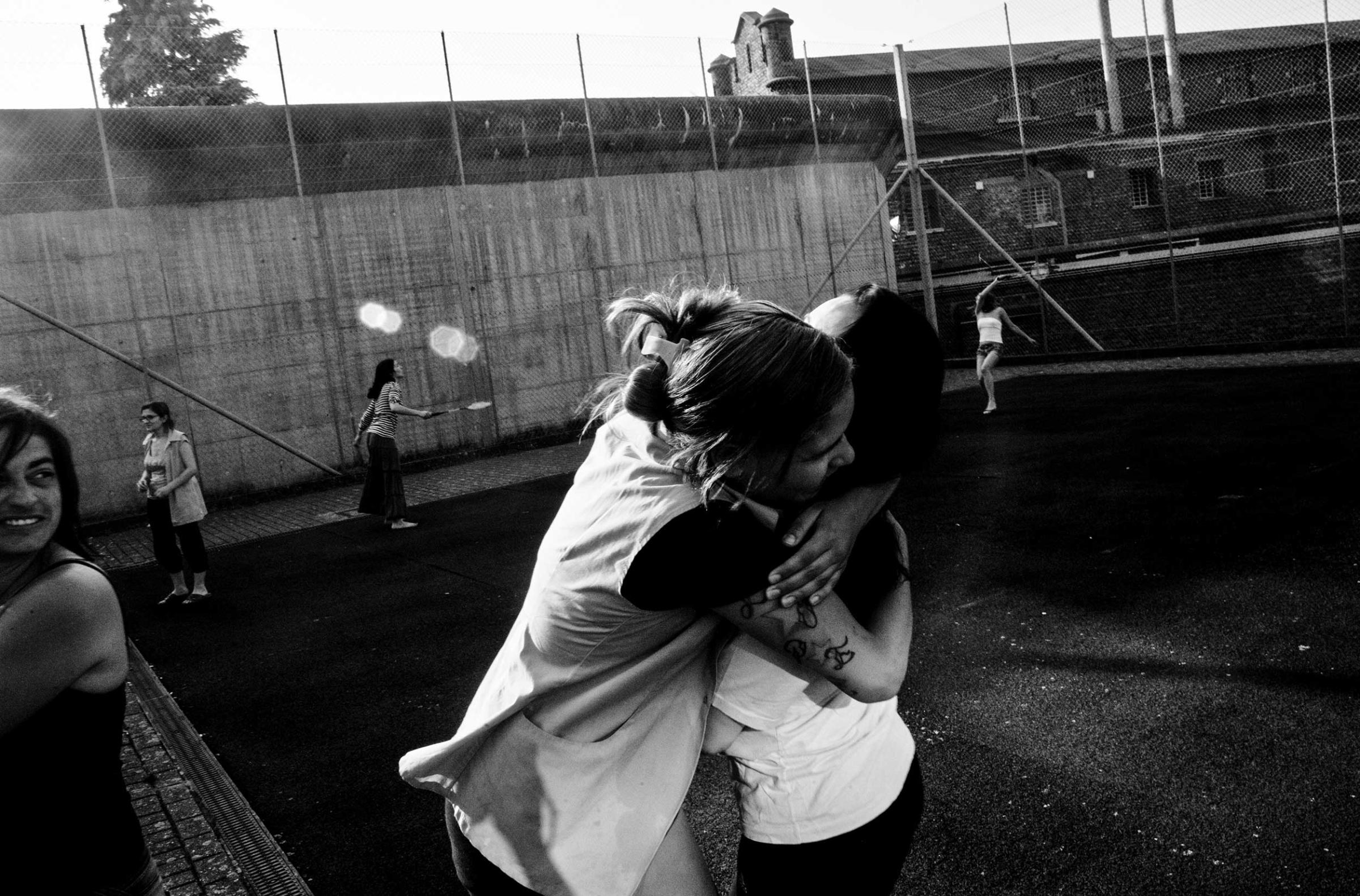 Two female prisoners hug during a badminton game in the courtyard of the prison for women in Berkendaele, Brussels, Belgium. July 2012.