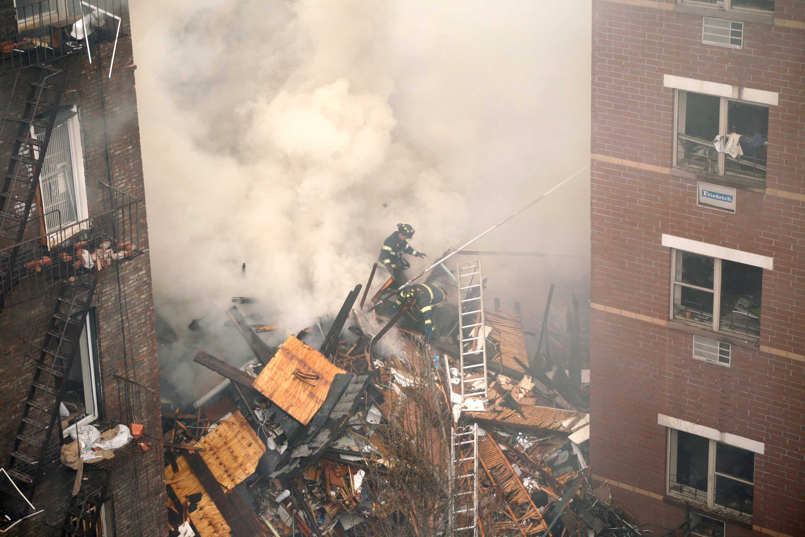Firefighters scale a vast pile of debris that remained after a gas leak explosion destroyed two buildings on Park Avenue in the East Harlem neighborhood of New York, March 12, 2014.