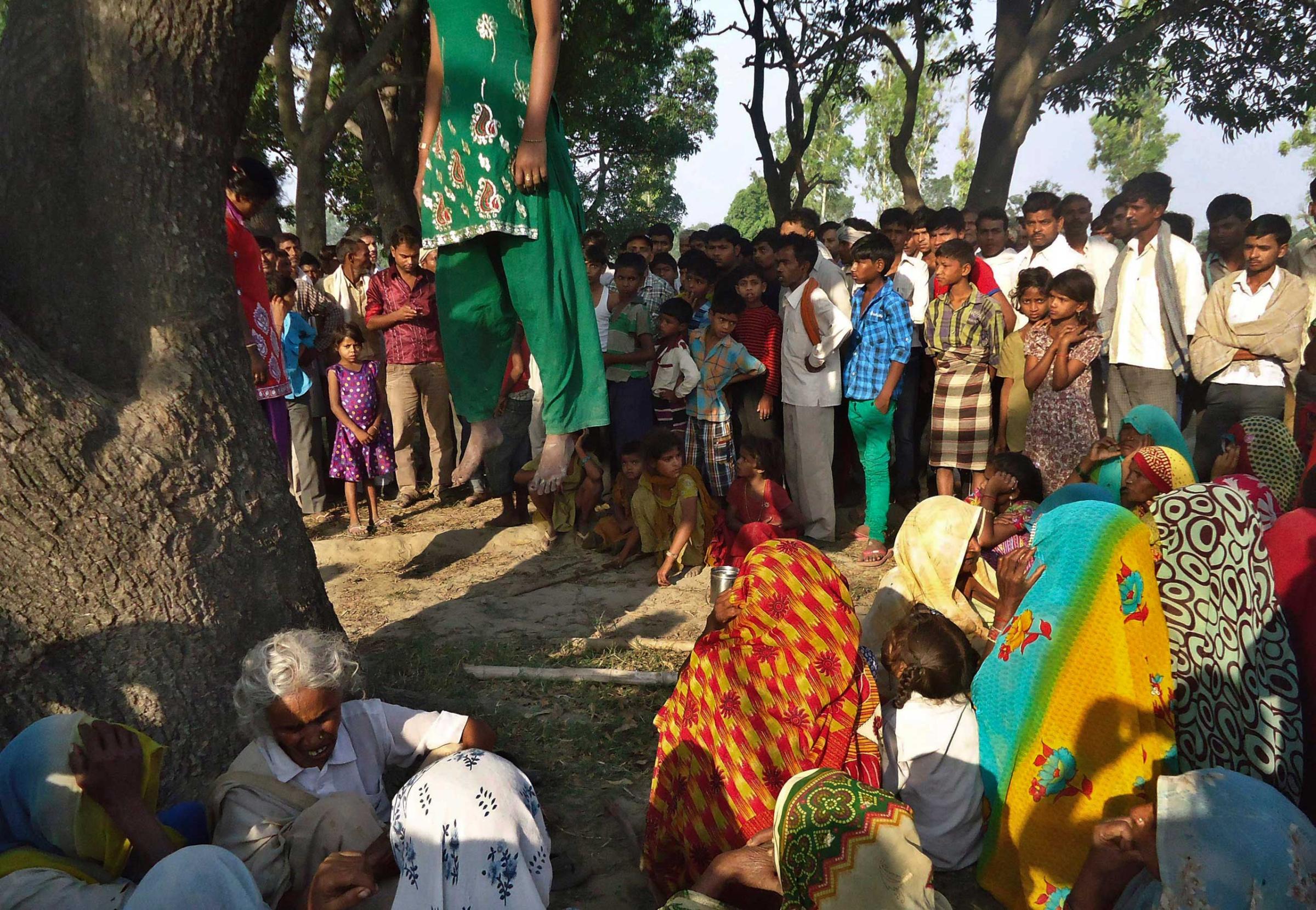 Indian villagers gather around the bodies of two teenage sisters hanging from a tree in Katra village in Uttar Pradesh state, India. The teenage sisters in rural India were raped and killed by attackers who hung their bodies from a mango tree, May 28, 2014.