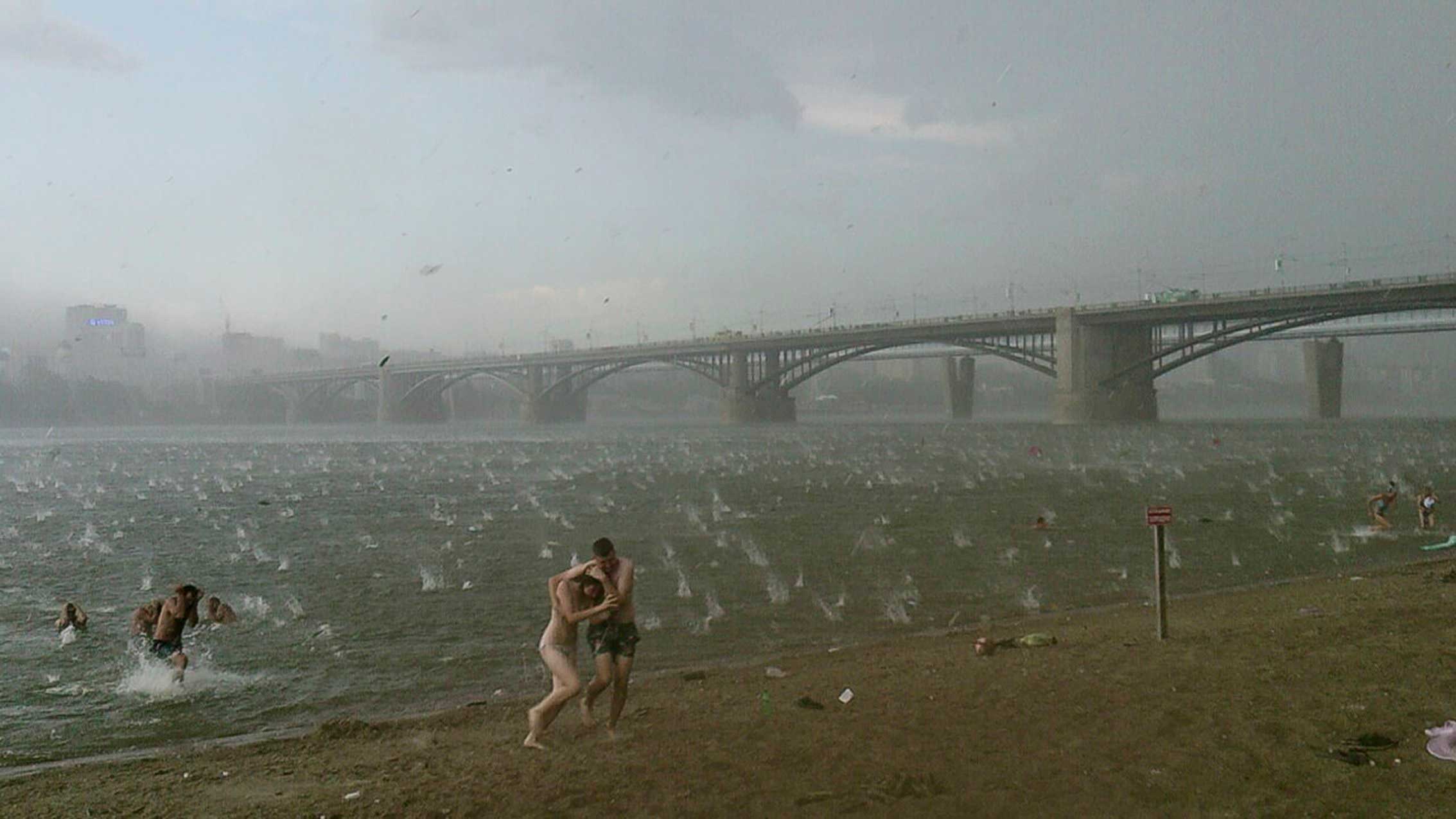People run to shelter from hailstorm on the beach at Ob River, Novosibirsk, Russia, July 12, 2014.