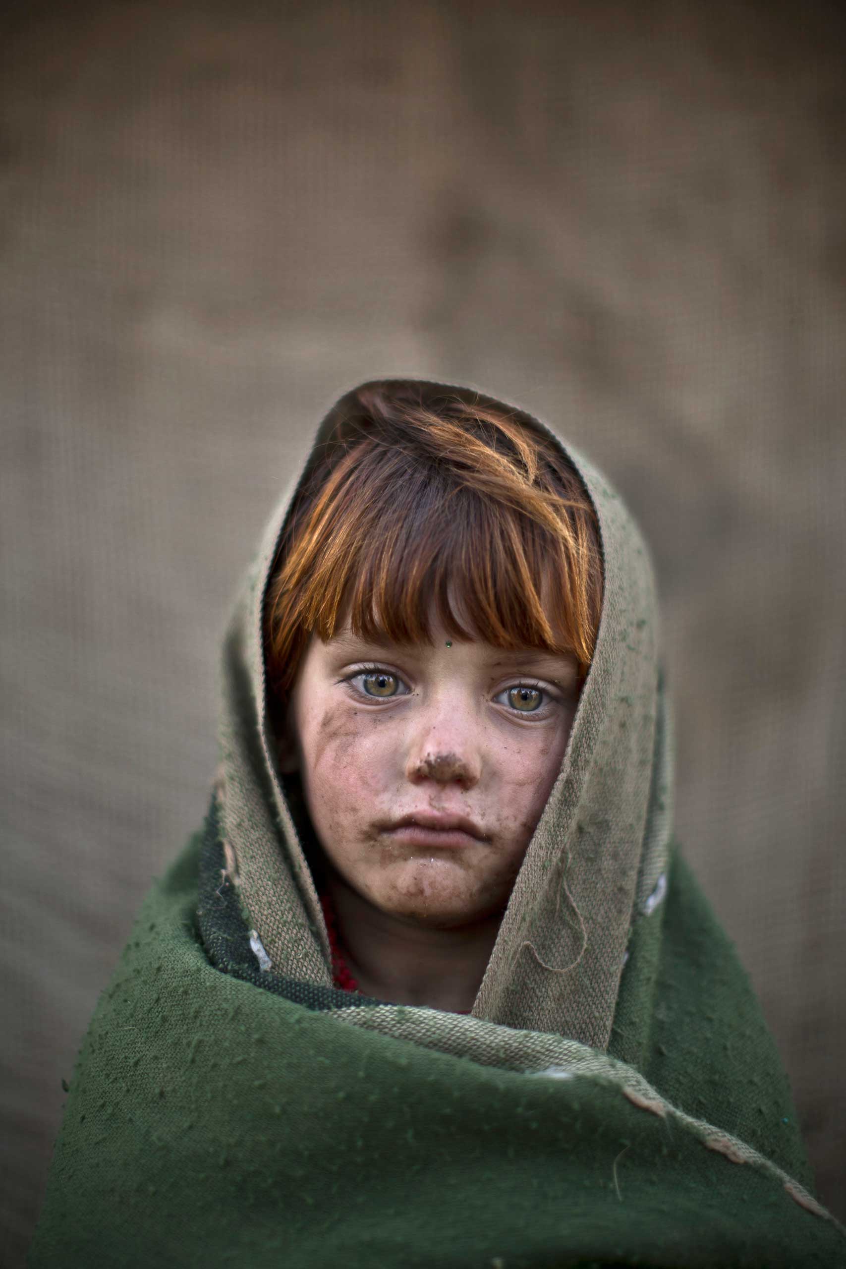 An Afghan refugee girl, laiba Hazrat, 6, poses for a picture, while playing with other children in a slum on the outskirts of Islamabad, Pakistan. Jan. 24, 2014.