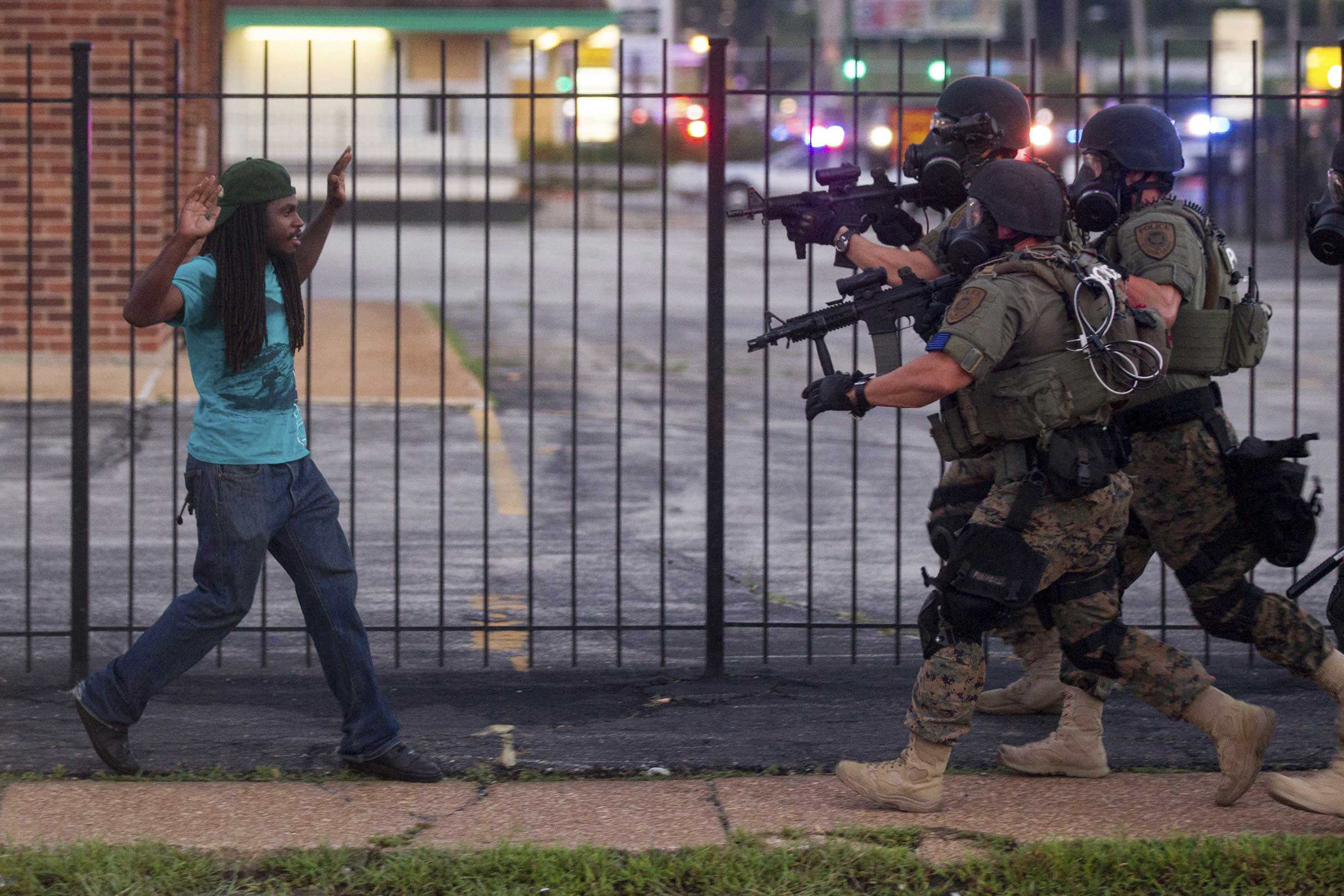 A man backs away as law enforcement officials close in on him and eventually detain him during protests over the death of Michael Brown in Ferguson, Mo., Aug. 11, 2014.