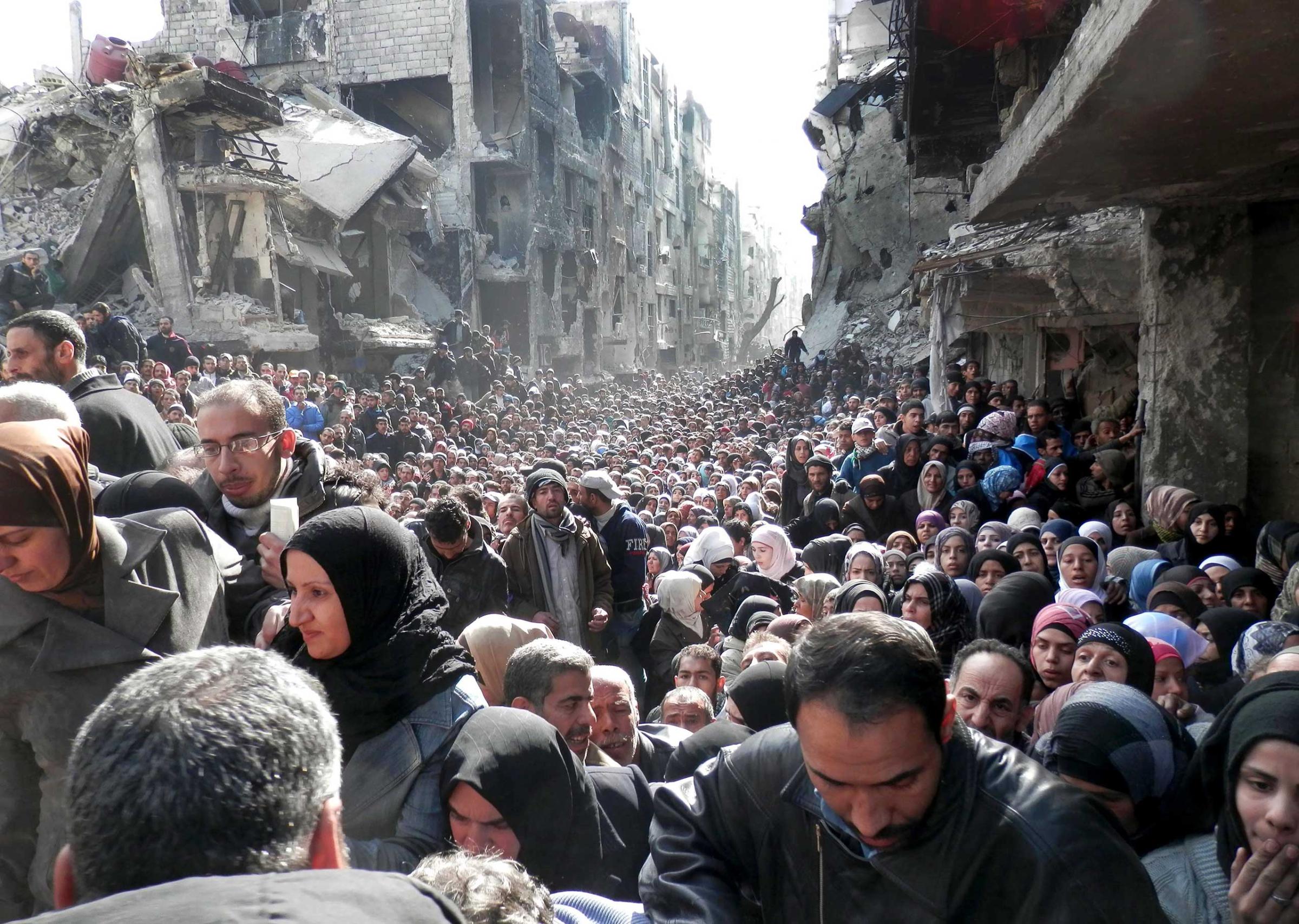 A handout photo of Palestinian refugees waiting for food aid in the Yarmouk camp on the outskirts of Damascus, Syria, Jan. 31, 2014.